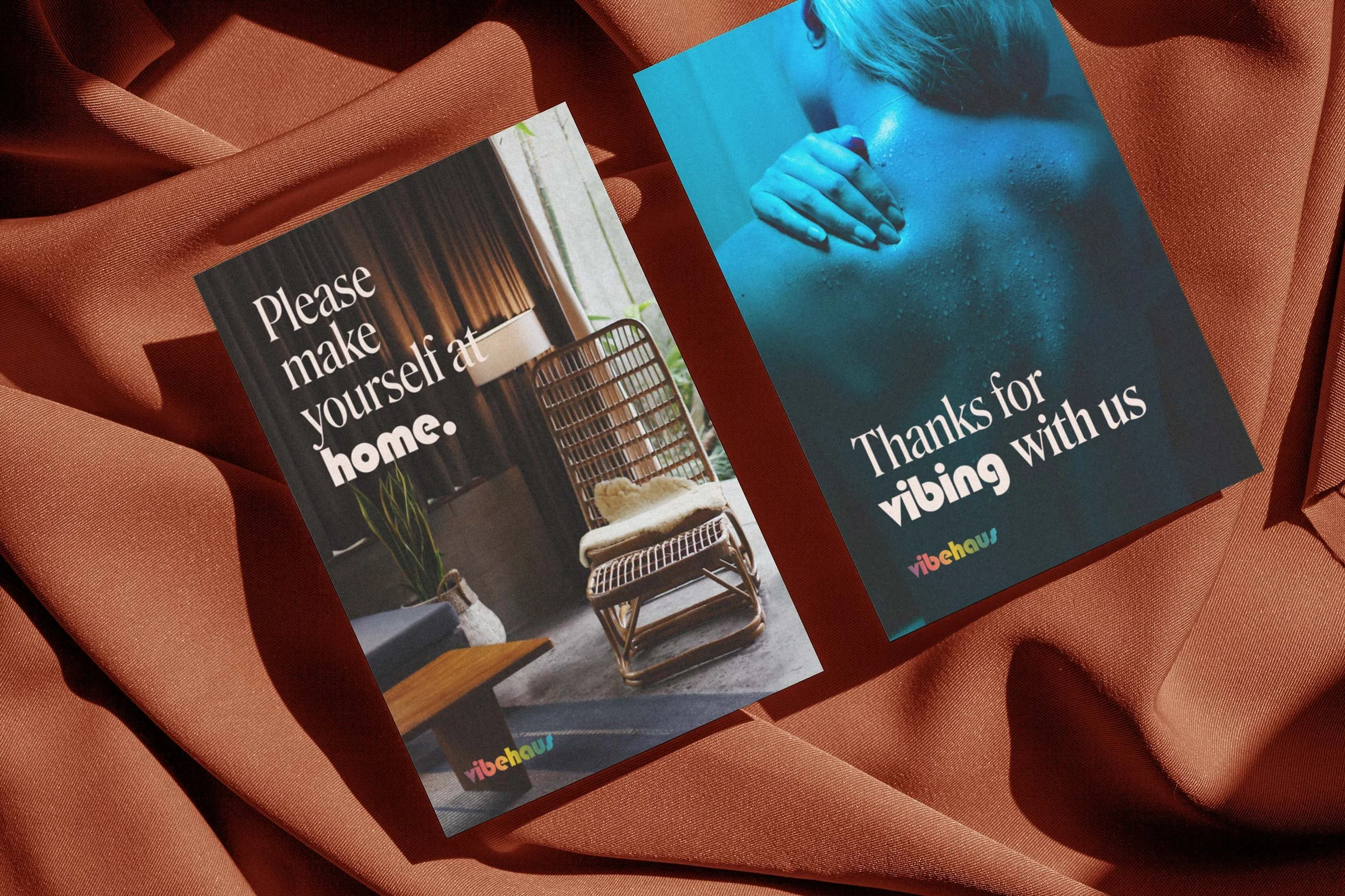 Two postcards on a reddish fabric background. The first postcard has a modern interior design scene with the text "Please make yourself at home." The second postcard shows a woman with wet skin, with the text "Thanks for vibing with us." The postcards are placed one overlapping the other.