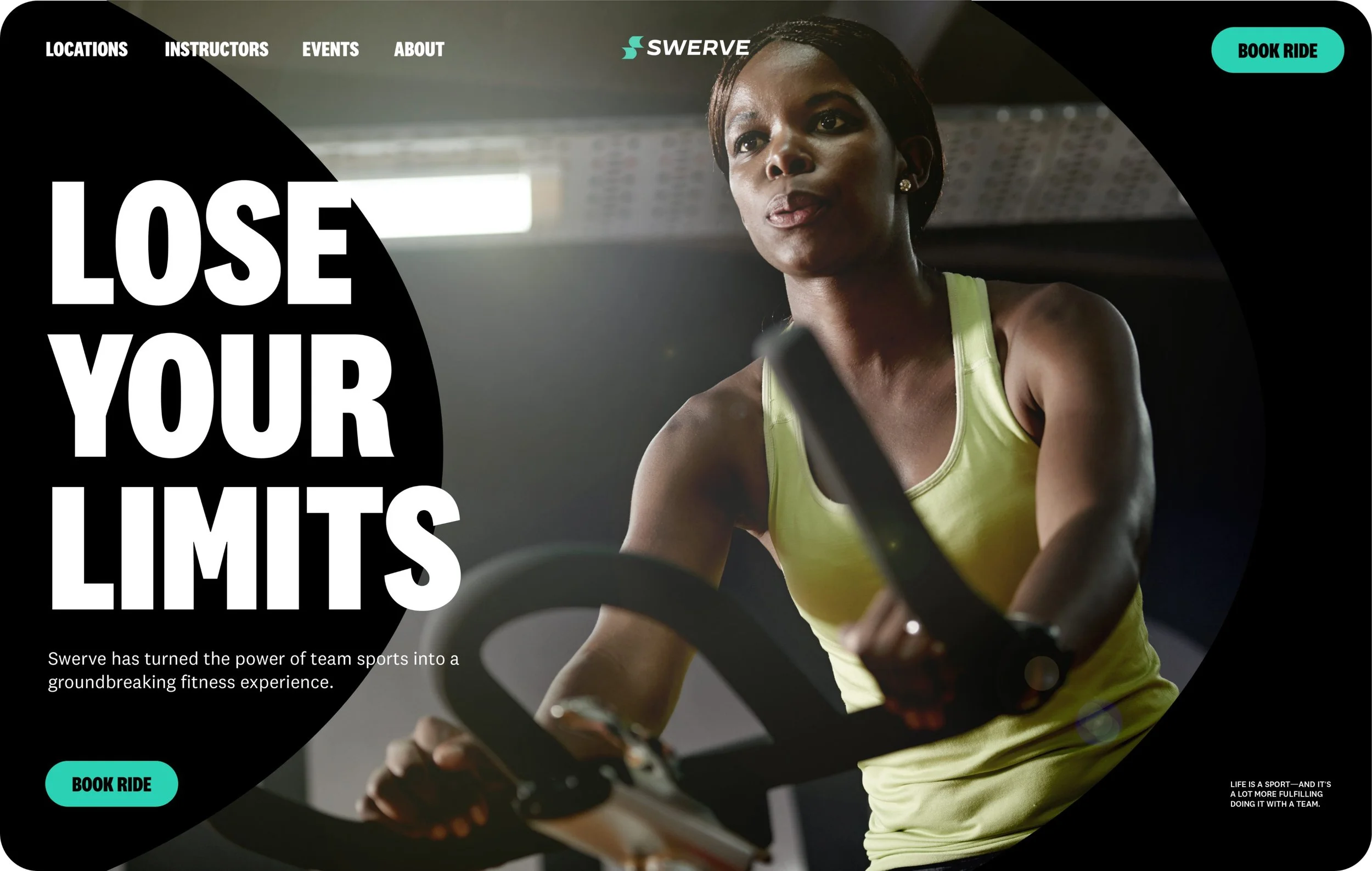 A woman with short hair wearing a yellow workout top, concentrating while riding a stationary bike in a gym with a dark background and overhead lights.