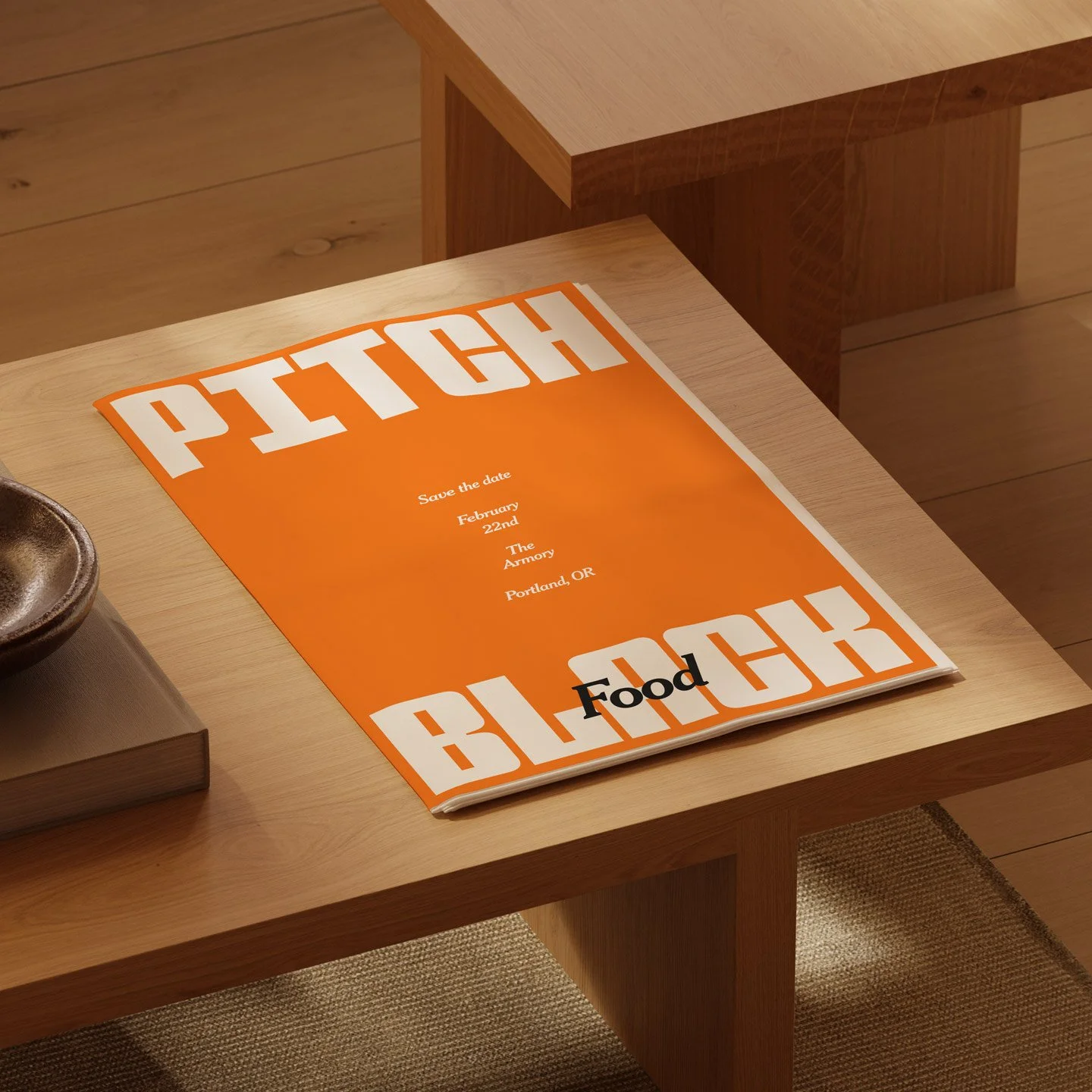A bright orange and white food event save the date poster on a light wood table. The poster mentions an event on February 22nd at The Armory in Portland, OR, with the word 'Food' at the bottom.
