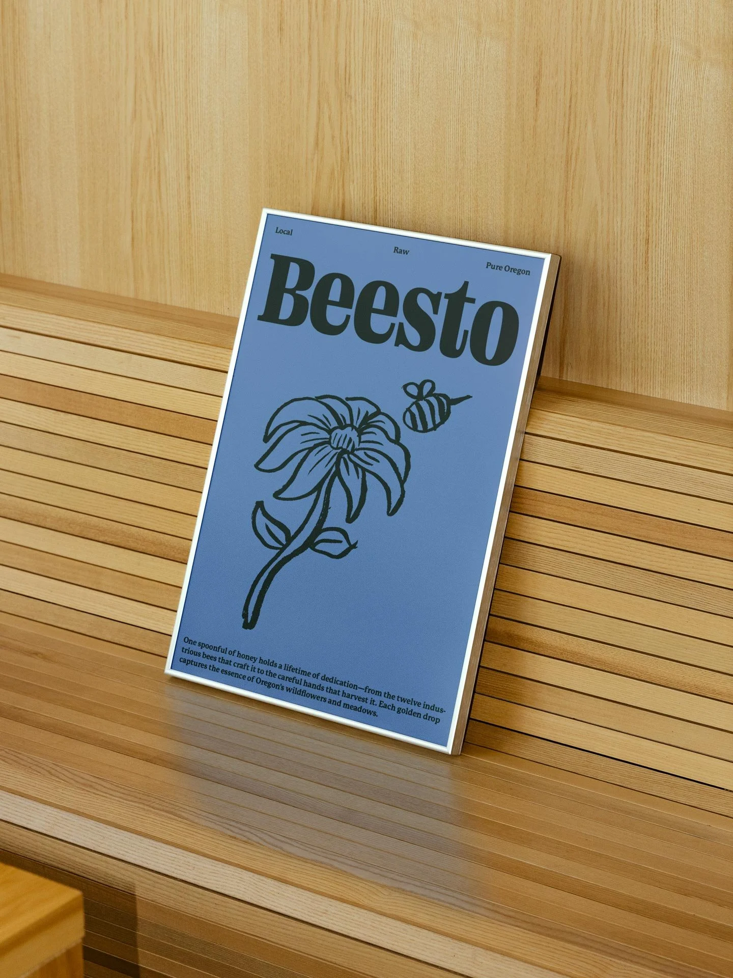 A poster with a blue background titled "Beesto" featuring a drawing of a bee and a flower, placed on a wooden bench against a wooden wall.