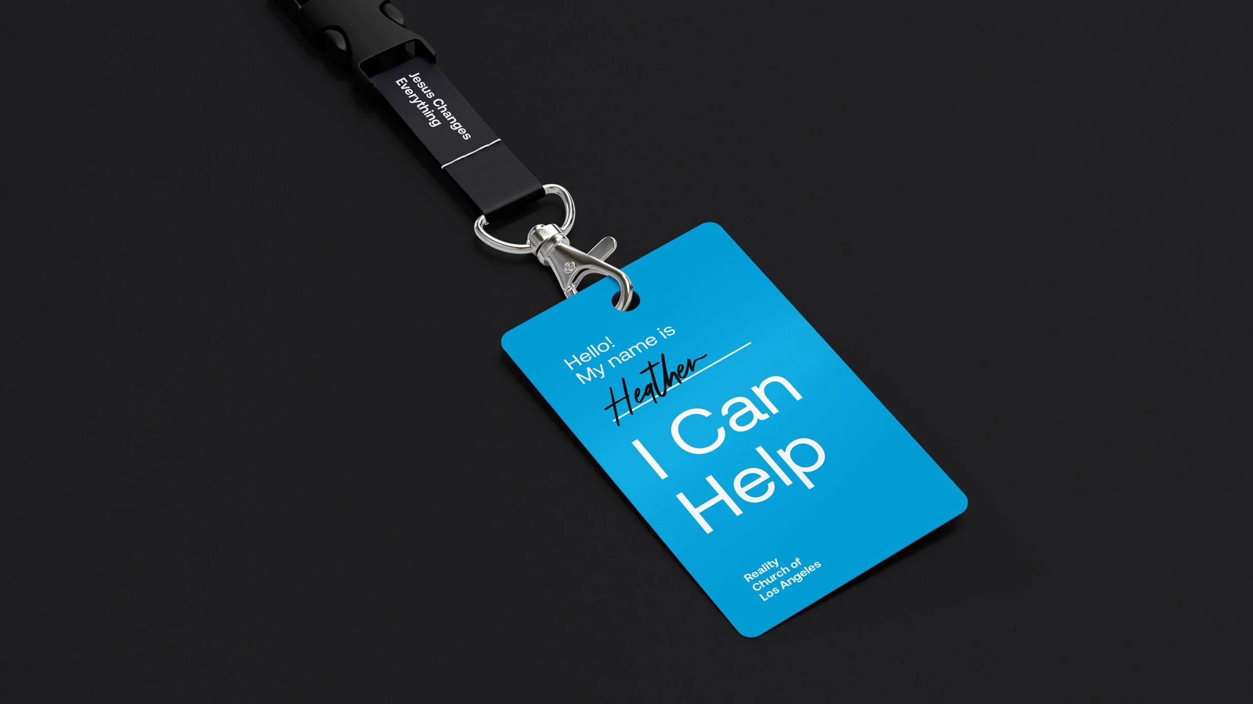 Blue name badge with white and black text attached to a black lanyard, on a black background.