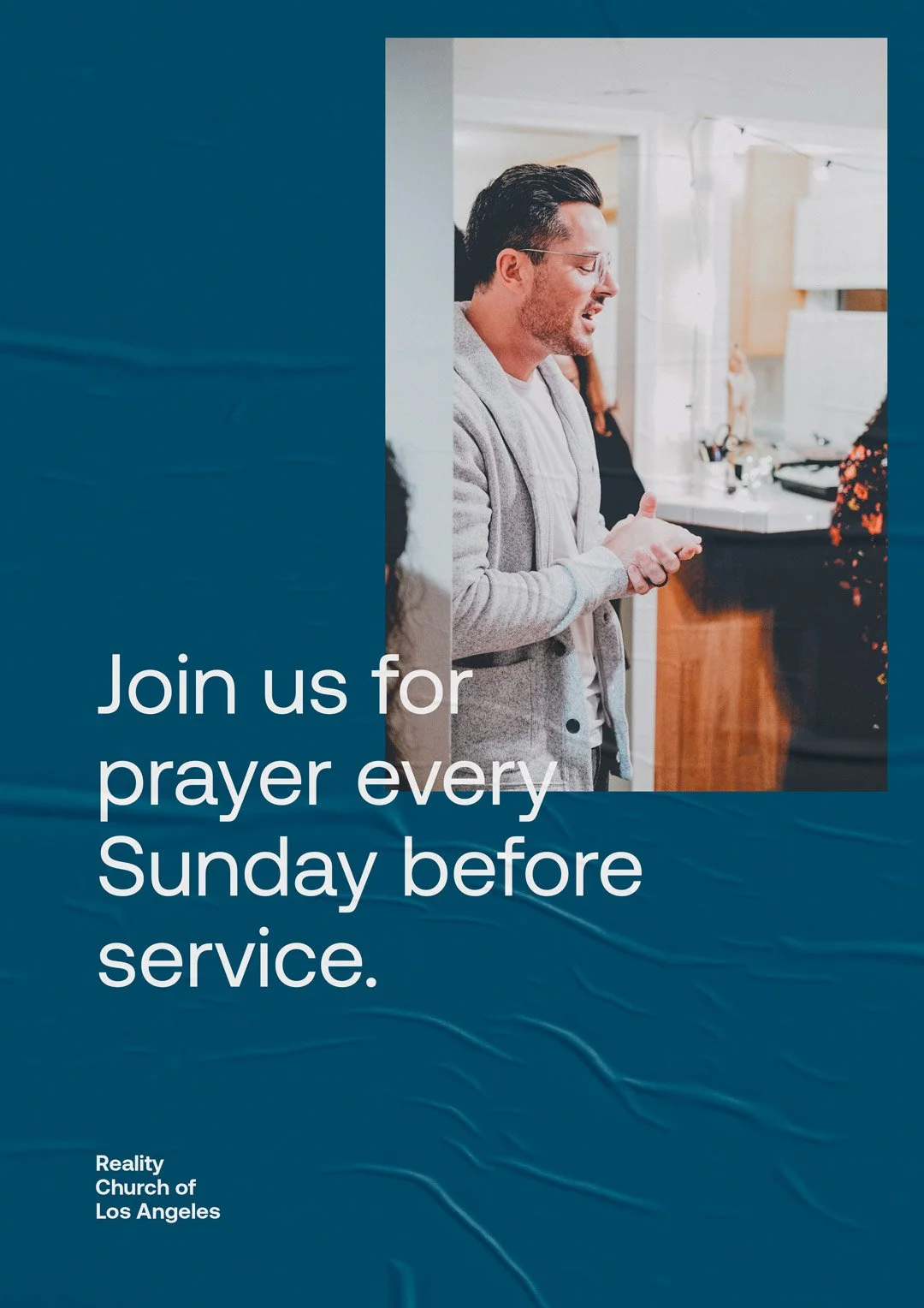 A man with glasses and a beard standing in a kitchen, smiling, with a woman in a floral shirt in the background. Overlaid on the image is text that reads, 'Join us for prayer every Sunday before service.' The bottom left corner has text that says, 'Reality Church of Los Angeles.'