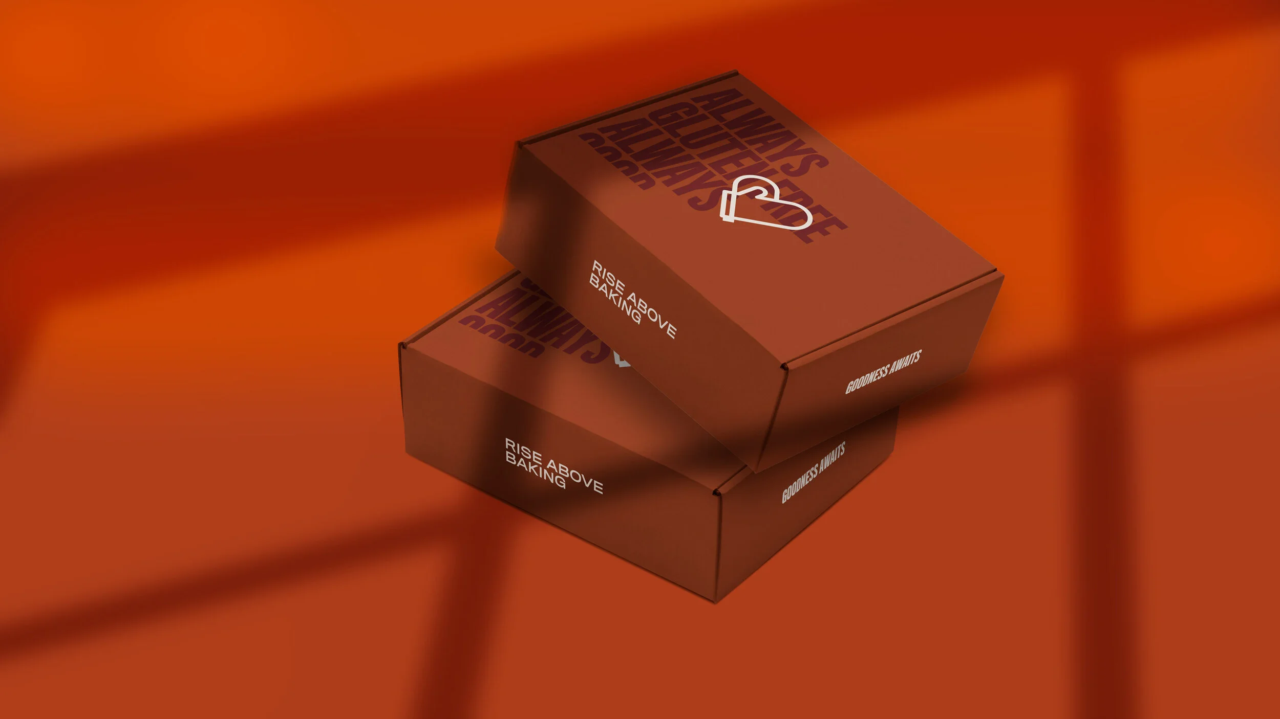 Two brown boxes with the text 'RISE ABOVE BAKING' and 'GOODNESS AWAITS'; one box on top of the other, against an orange background.
