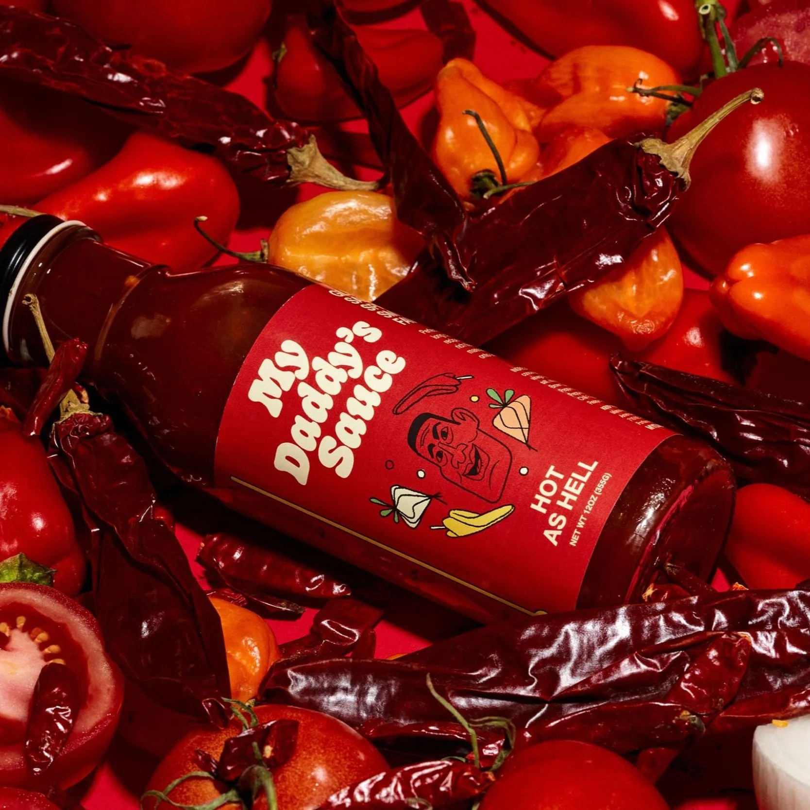 A bottle of Dave's Famous Sauce surrounded by red and orange chili peppers, cherry tomatoes, and other fresh vegetables on a red background.