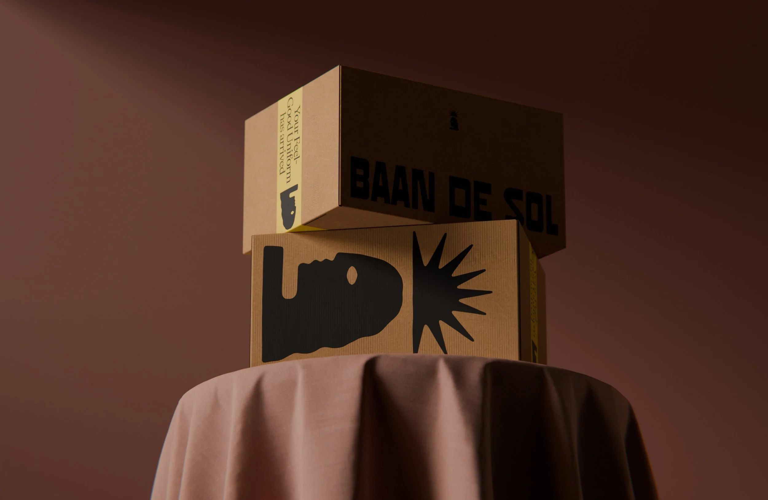 Close-up view of stacked cardboard boxes with labels, placed on a round surface covered with a cloth, against a plain dark background.