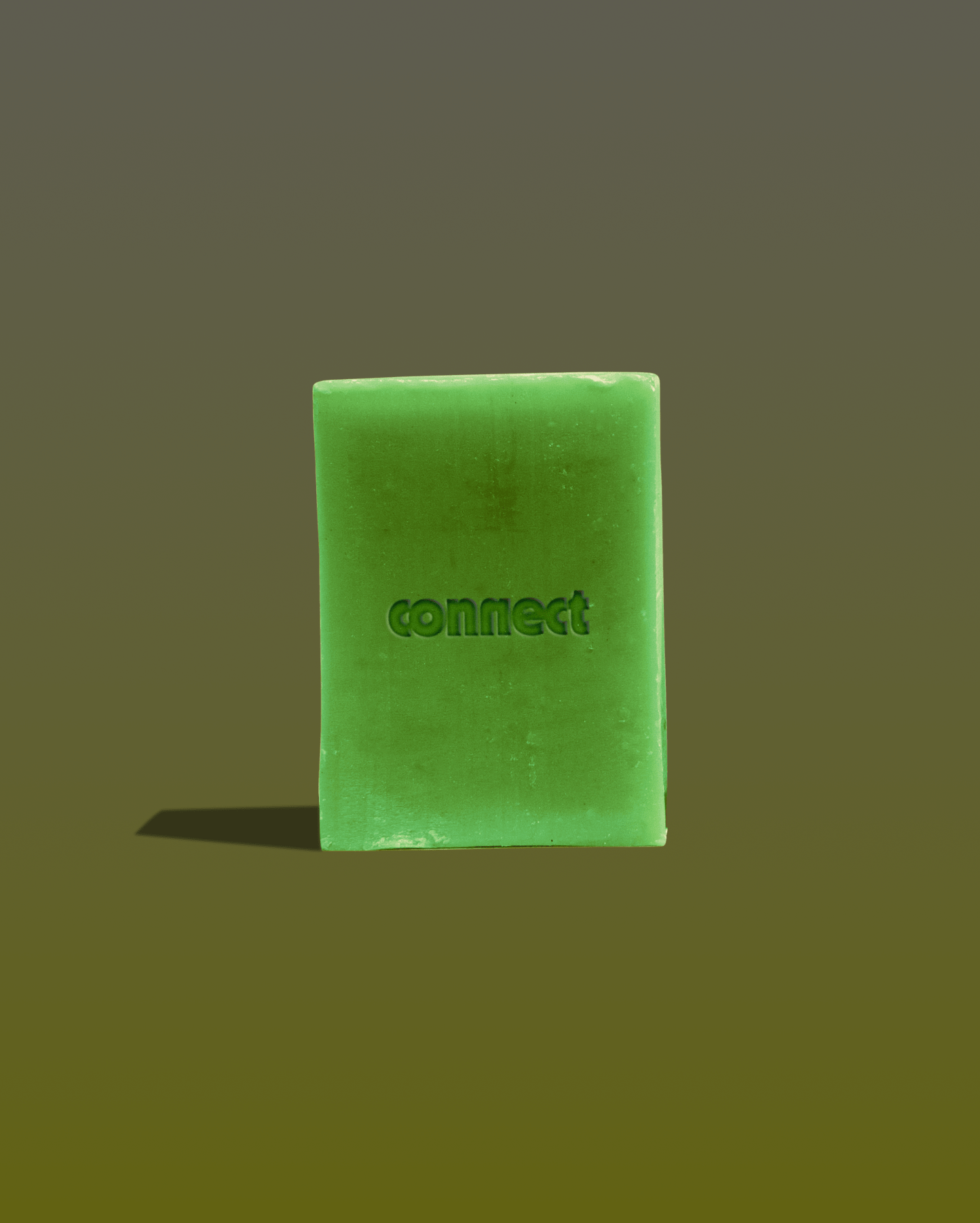 A green soap bar with the word 'connect' embossed on it, standing upright with a shadow cast on the surface below.