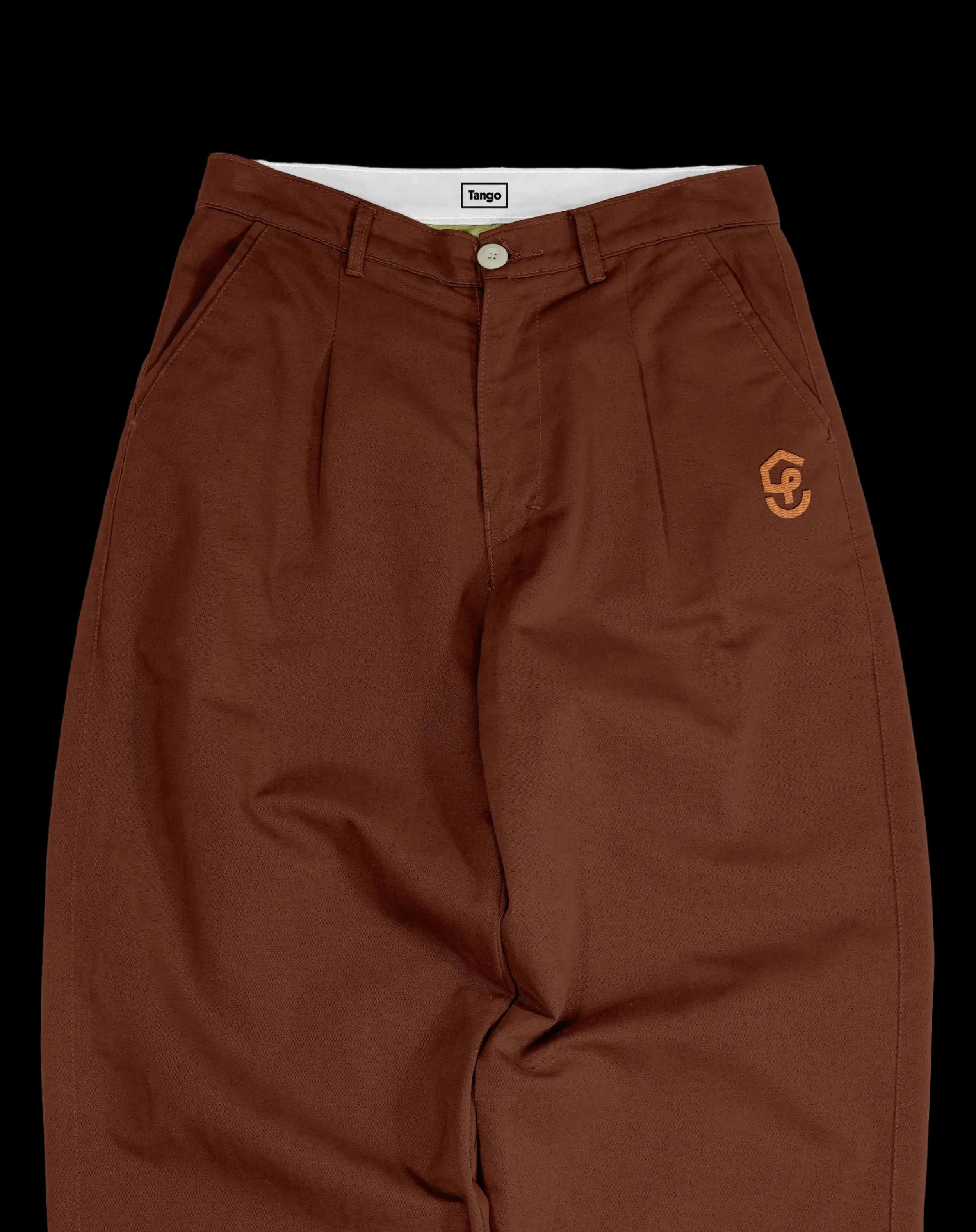 A close-up view of a pair of brown pants with a white button, belt loops, and a small logo on the bottom right corner, against a black background.