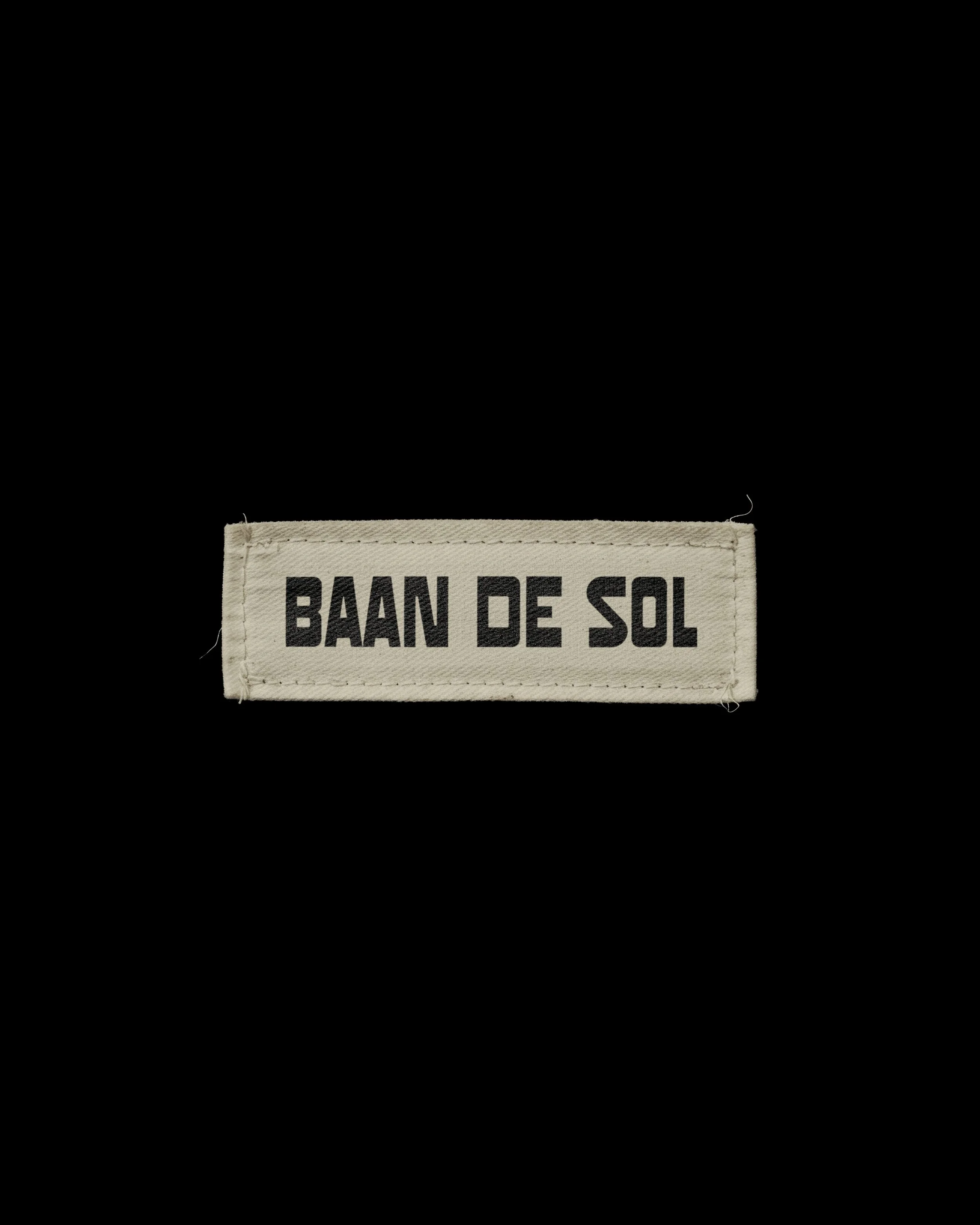 Close-up of a fabric label with the words 'BAAN DE SOL' stitched on it.