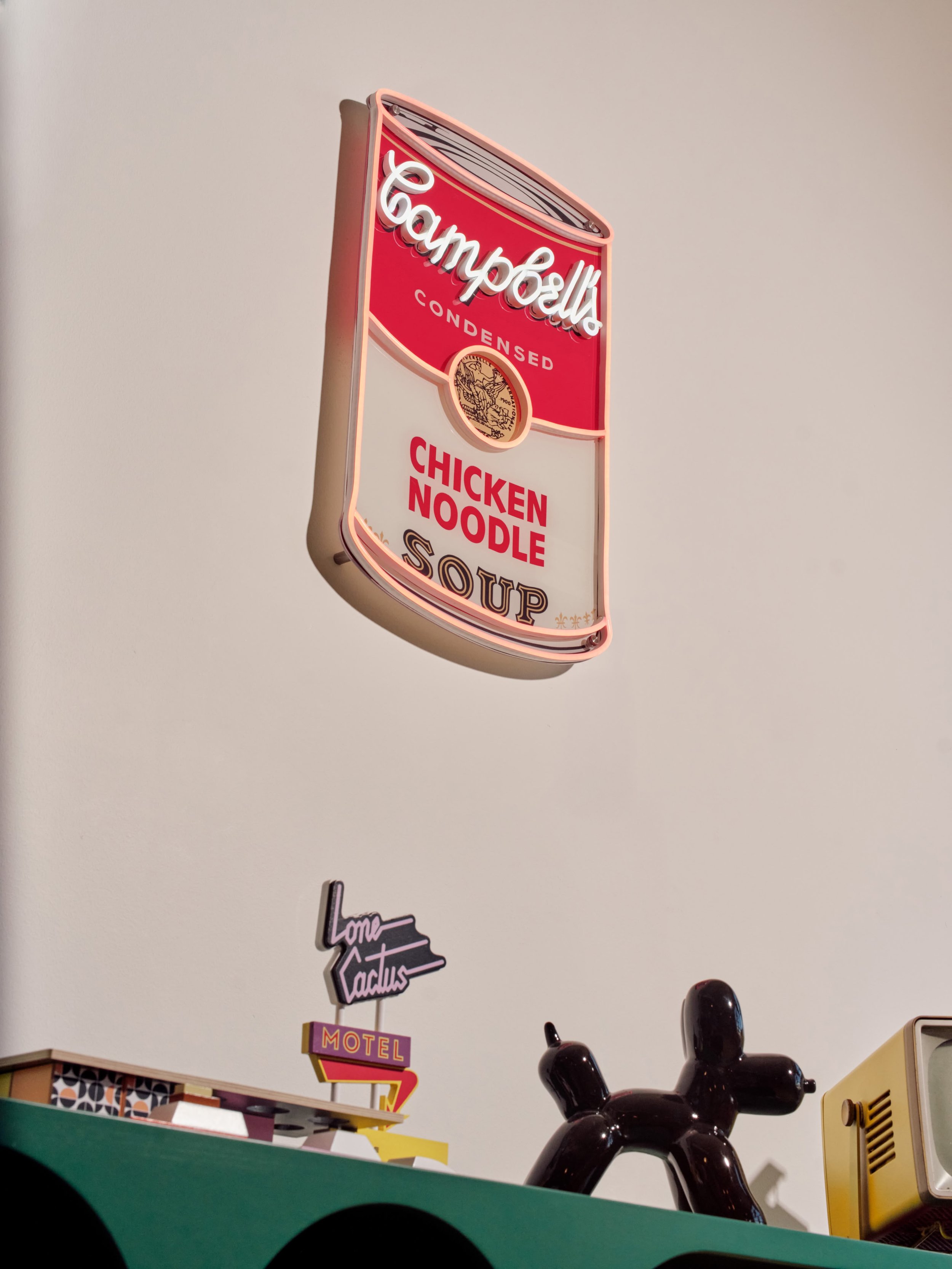 Neon sign depicting a Campbell's Condensed Chicken Noodle Soup can with red, white, and gold colors.