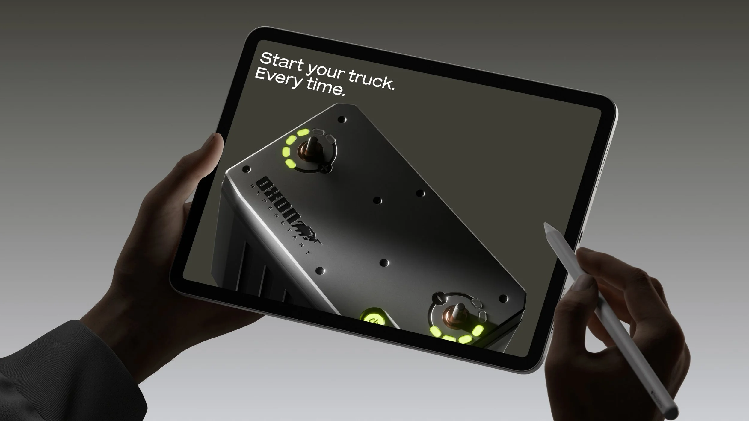 A person uses a stylus to interact with a digital tablet displaying a virtual control panel for starting a truck engine, with text that reads 'Start your truck. Every time.'