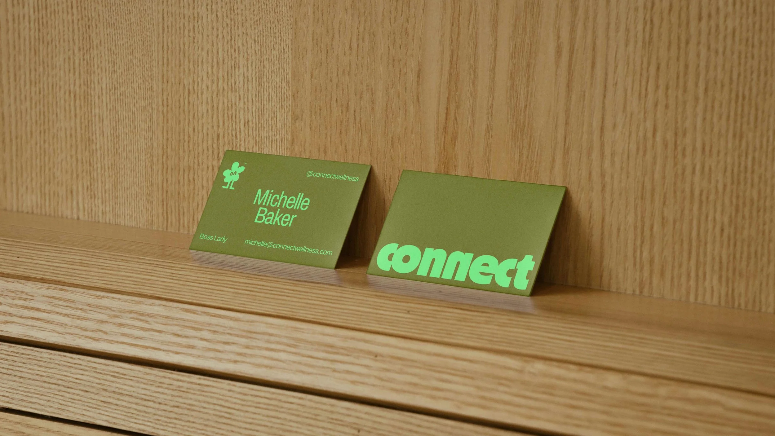 Green business card and paper slot with the word 'connect' on a wooden shelf.