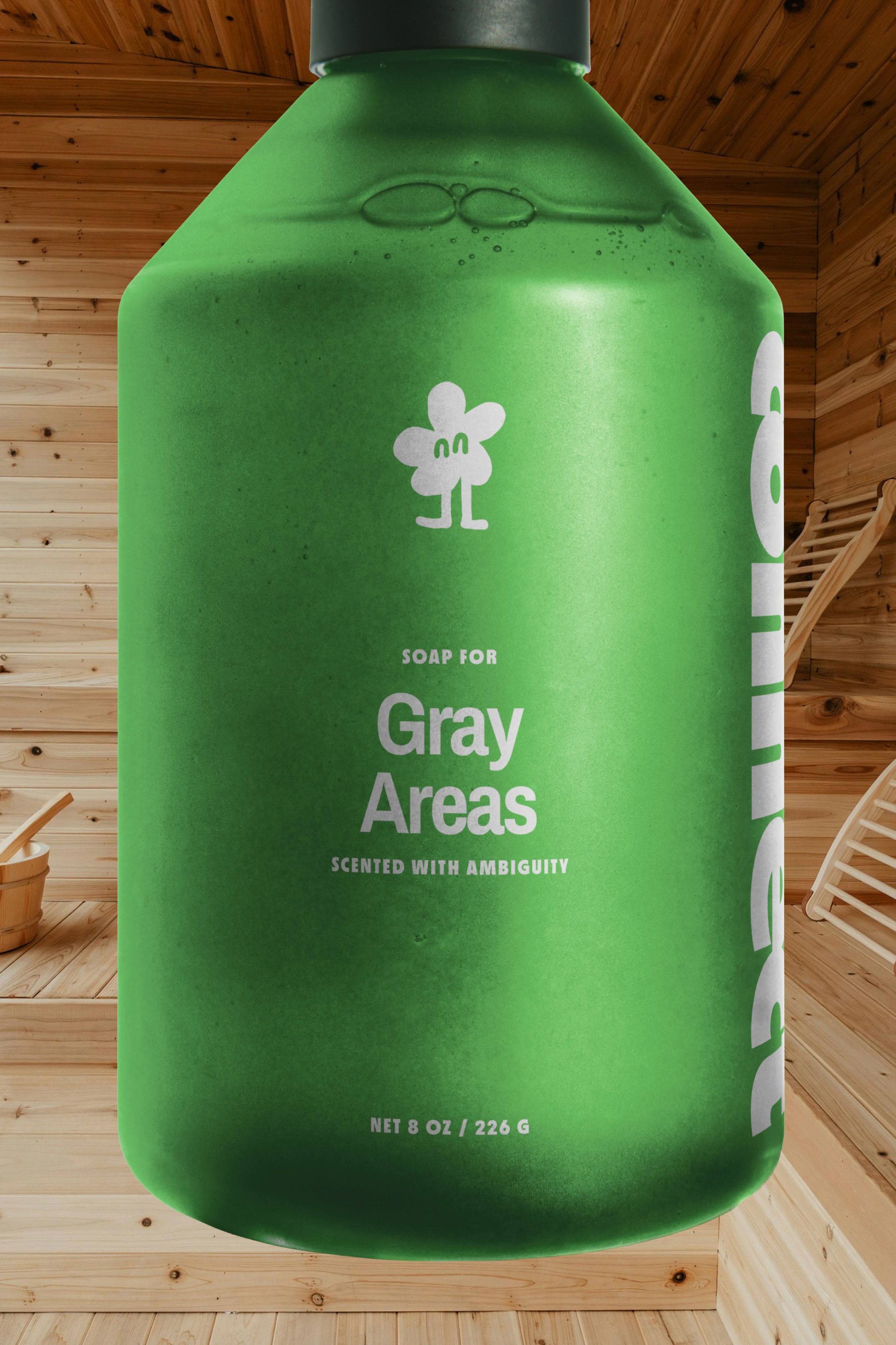 Close-up of a green soap bottle with white label text reading 'Soap for Gray Areas', placed on a wooden surface with wooden walls in the background.