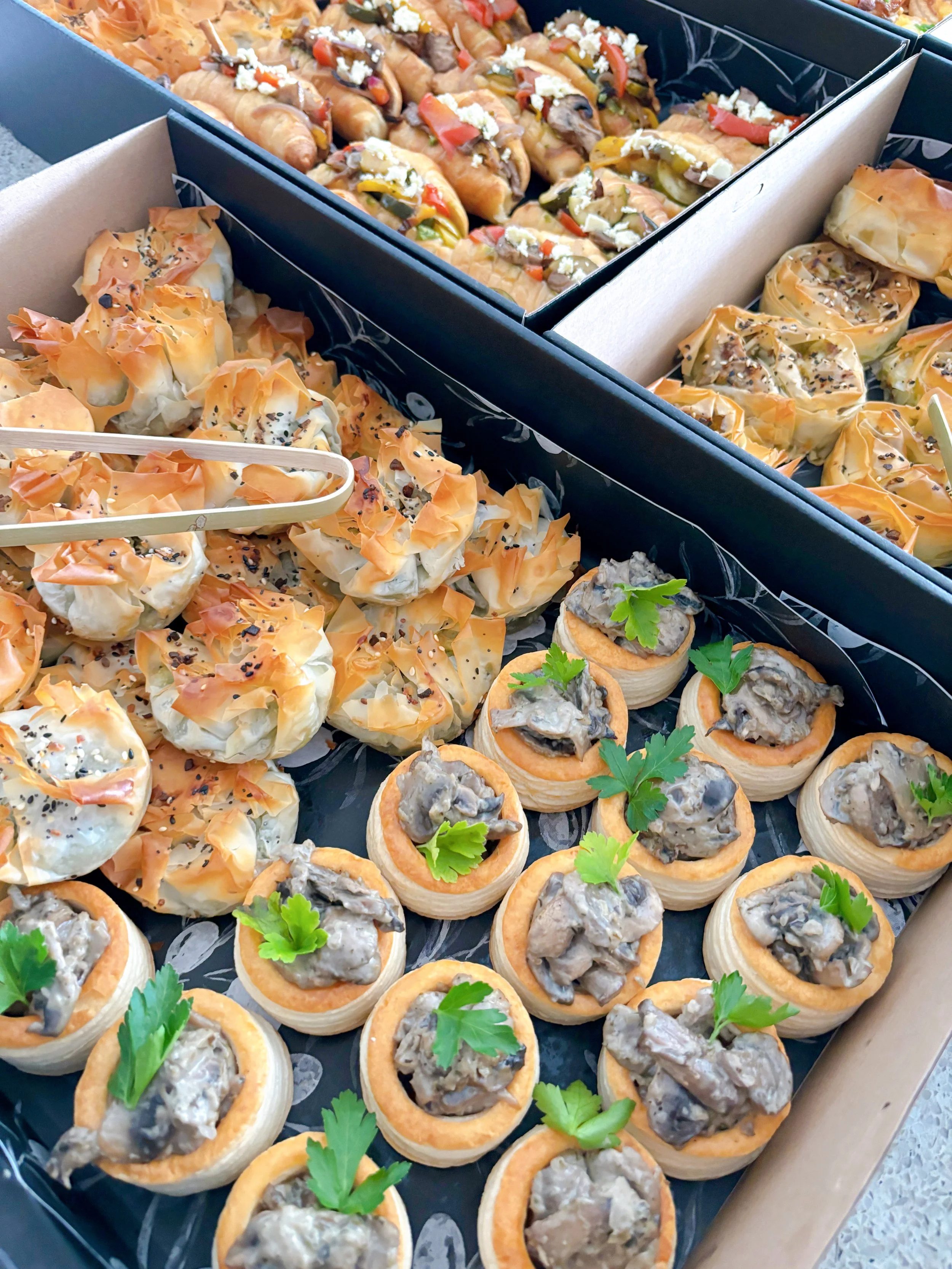 Tray of assorted appetizers, including mini vol au vents topped with creamy mushroom sauce and garnished with parsley, and puff pastry bites filled with cheese and toppings.