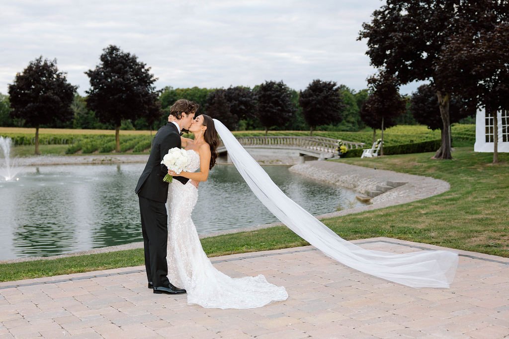 Bride and groom sharing a kiss at an elegant outdoor wedding venue with a pond and gardens in the Greater Toronto Area