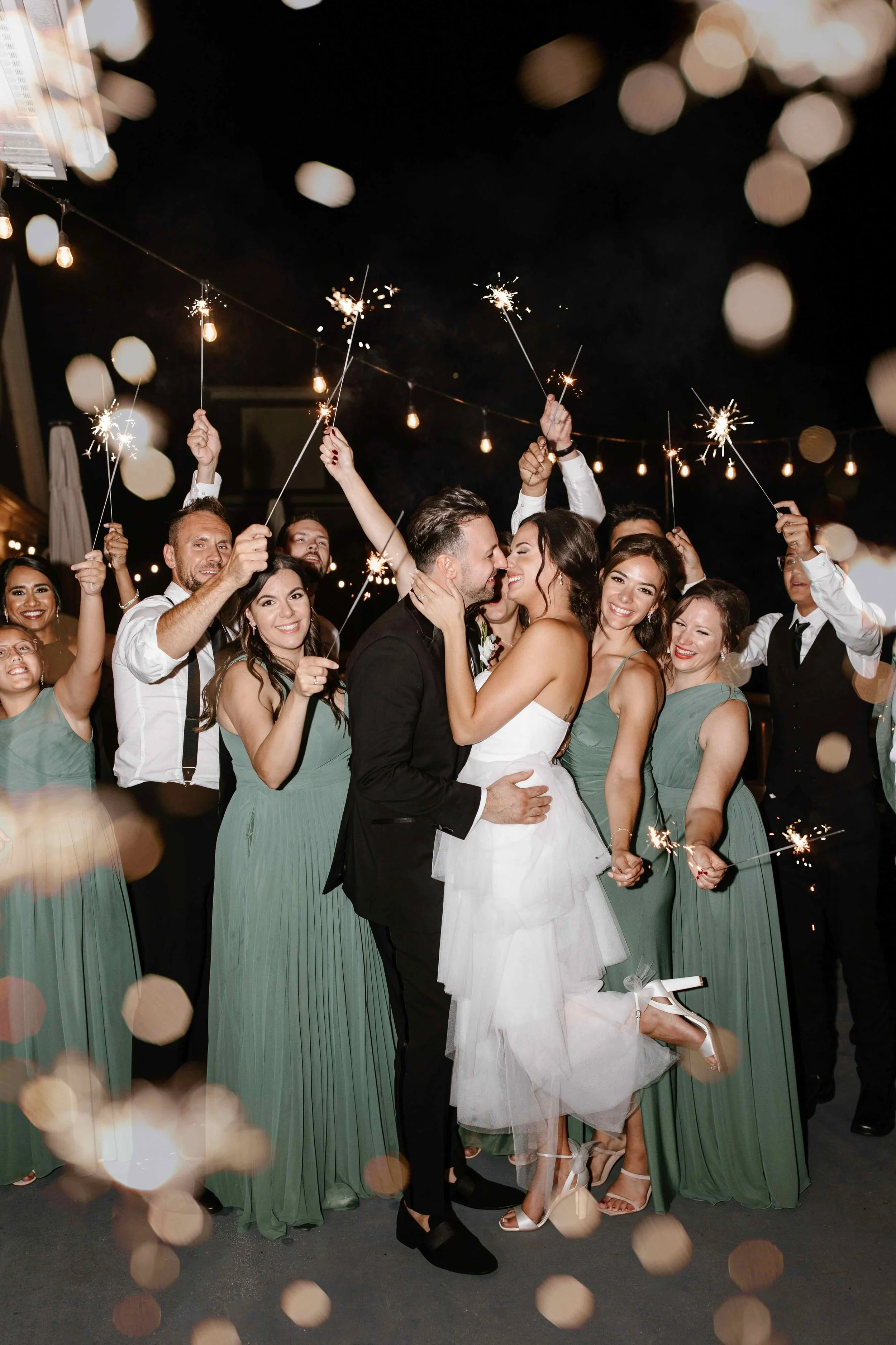Bride and groom sharing a kiss surrounded by wedding guests holding sparklers at a GTA wedding reception