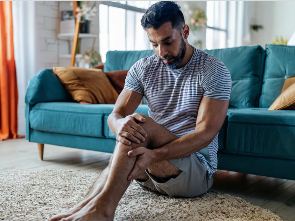 person holding tired leg showing early symptoms of poor circulation in the legs