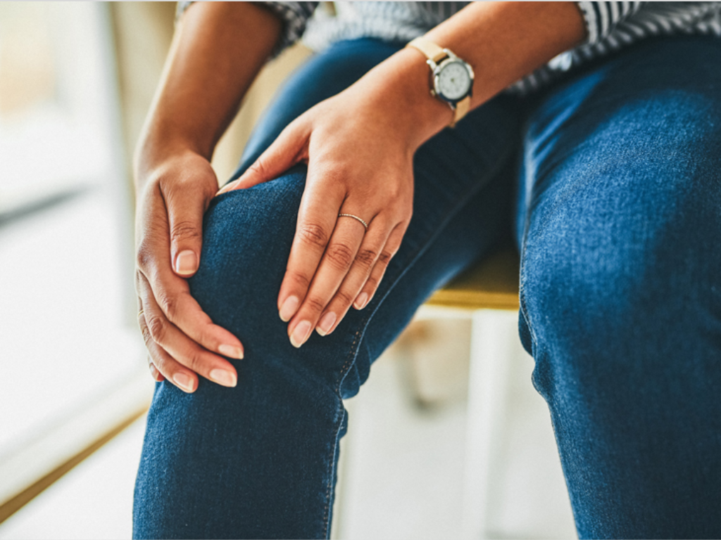 woman holding knee showing leg discomfort that may indicate reduced circulation or peripheral artery disease