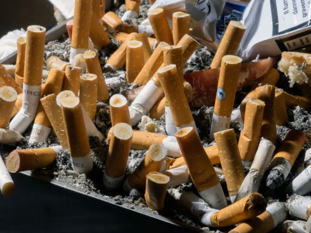 ashtray filled with cigarette butts representing nicotine use as a major risk factor for peripheral artery disease