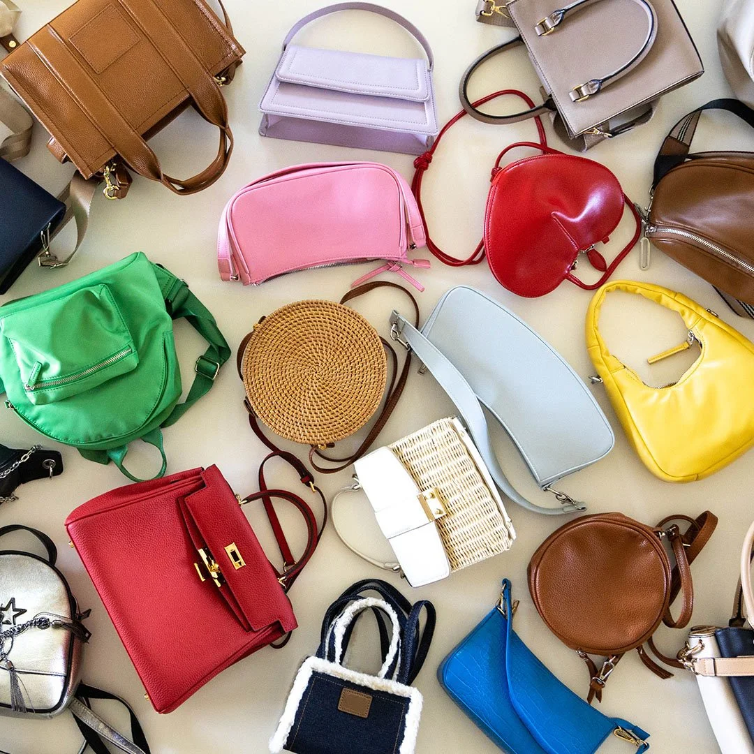 A collection of colorful handbags and purses of various styles and sizes on a white surface.