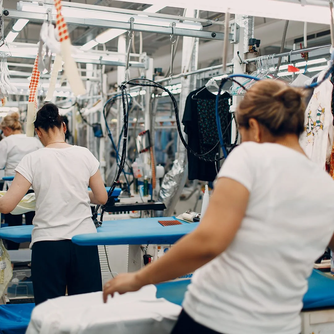 Women working in a textile factory with sewing machines and clothing.