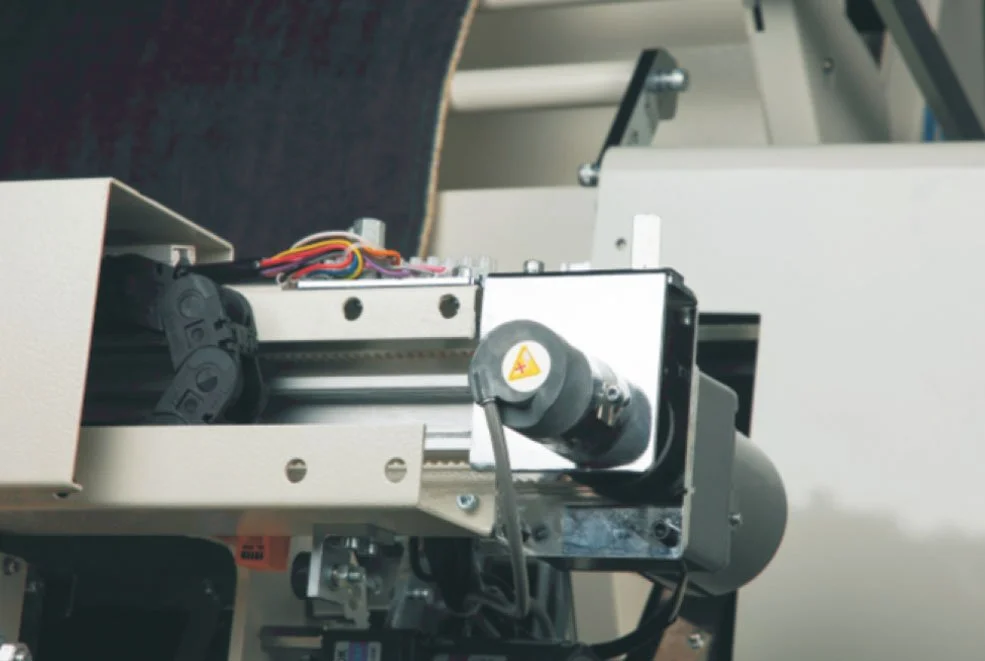 Close-up of a mechanical device with wires and a motor, part of a larger machine or apparatus.