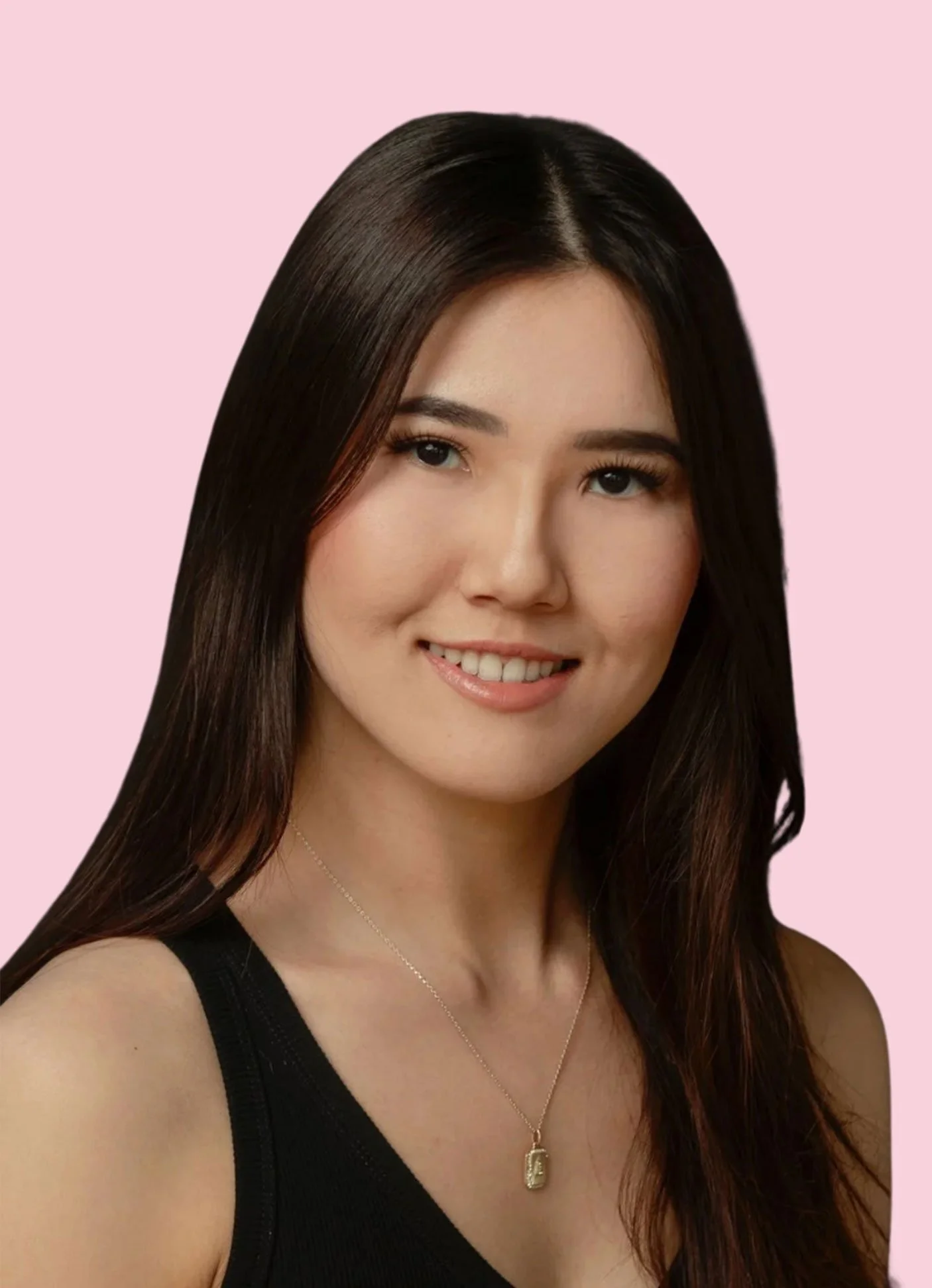 A portrait of a woman with long dark hair, wearing a black sleeveless top and a gold necklace with a small rectangular pendant, smiling at the camera against a pink background.