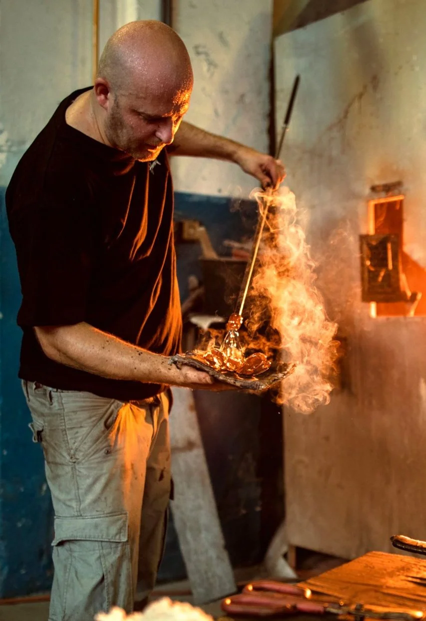 A blacksmith is heating and shaping metal in a workshop with flames and sparks.
