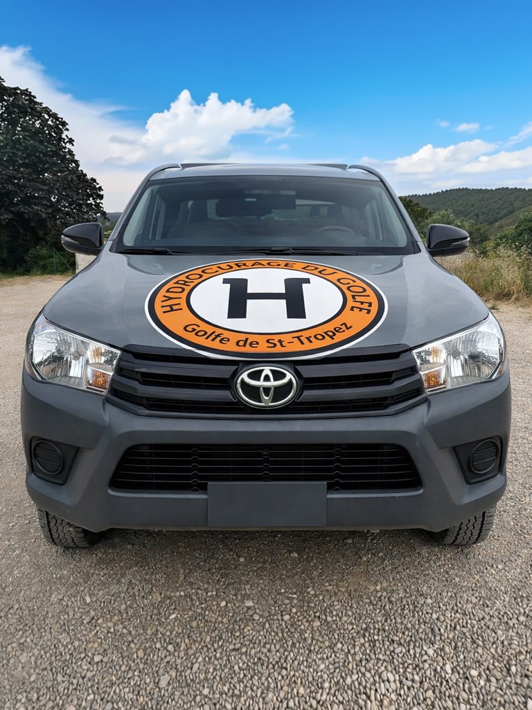 Véhicule de l'entreprise Hydrocurage du Golfe, stationné sur une surface en gravier, avec texte indiquant services de débouchage, curage, inspection par caméra et recherche de fuite, ainsi qu'un numéro de téléphone et une adresse email.