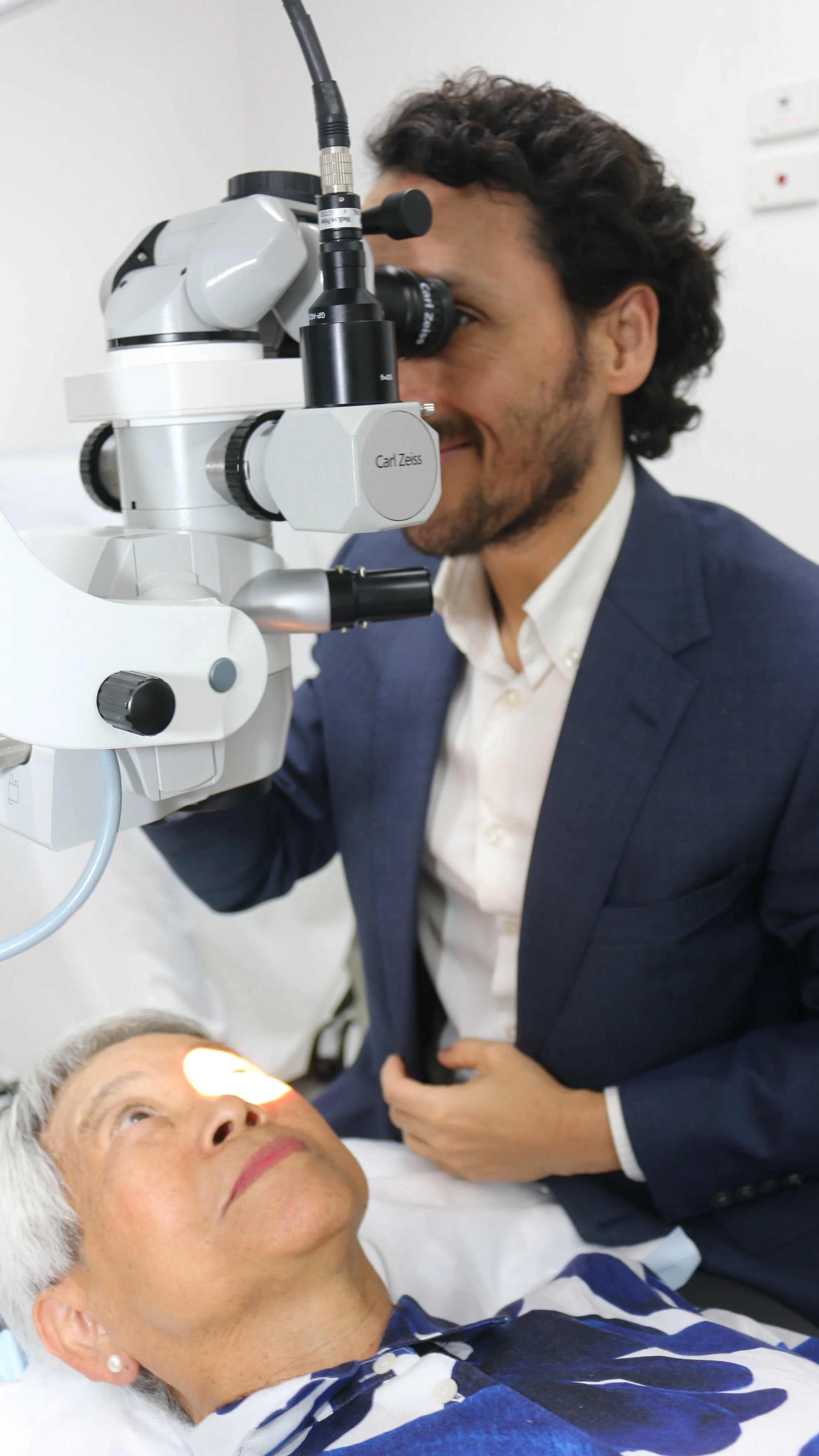 A doctor  at VisionCare Eye Specialists using a binocular microscope to examine a patient during an eye exam.