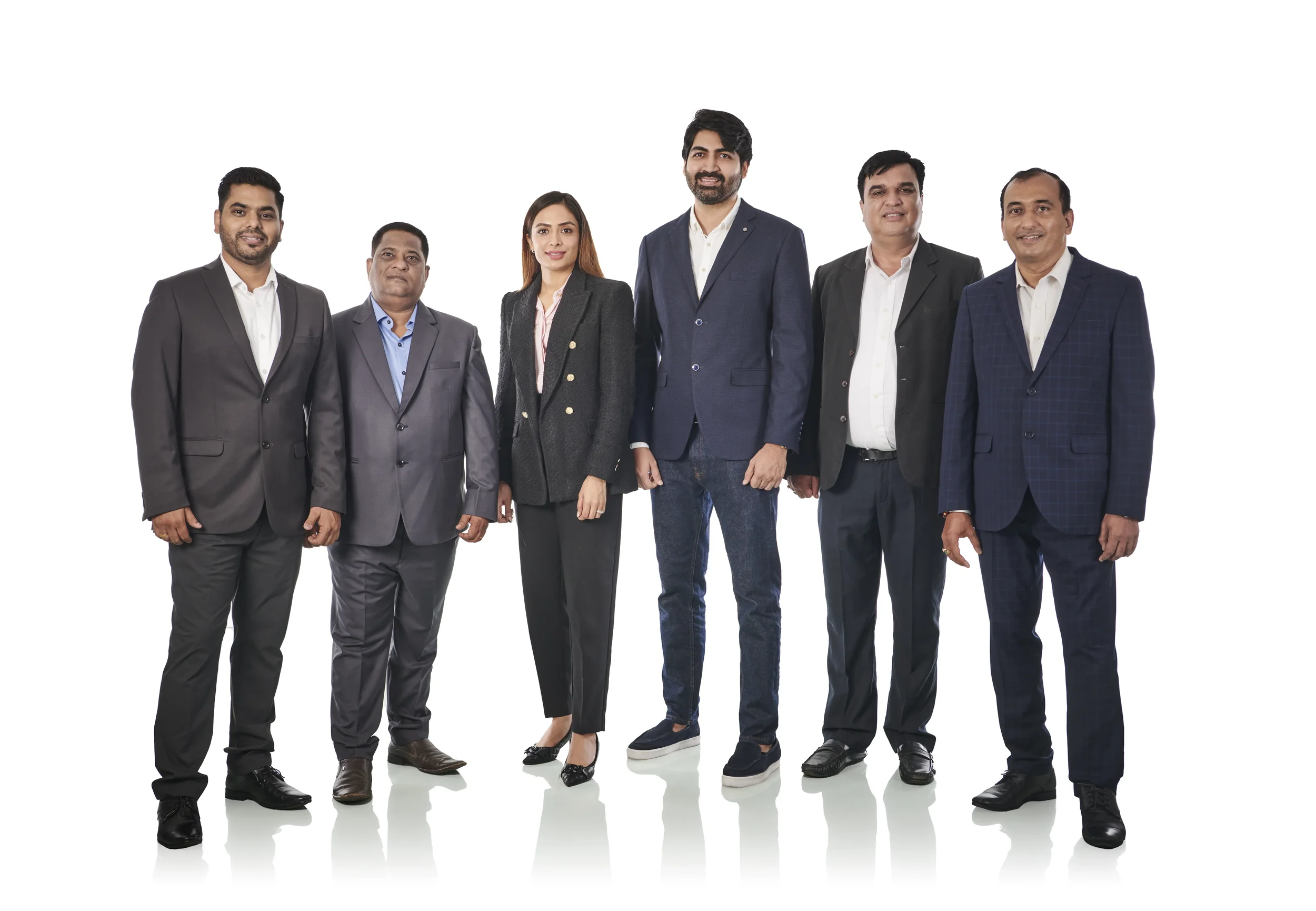 Group of six diverse professionals in formal business attire standing together against a white background.