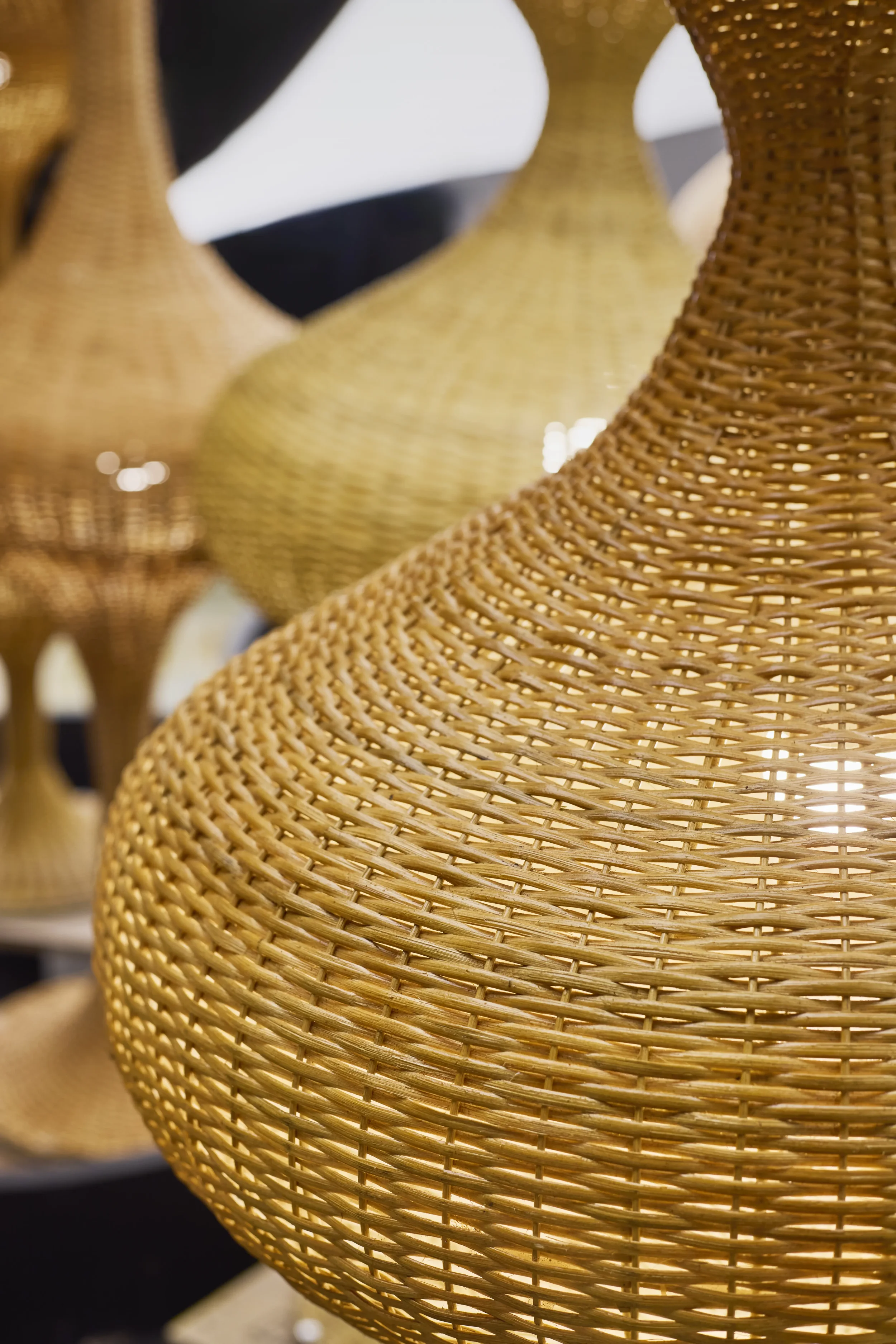 Close-up of woven rattan vases in shades of brown and tan, on display in a store or exhibit.