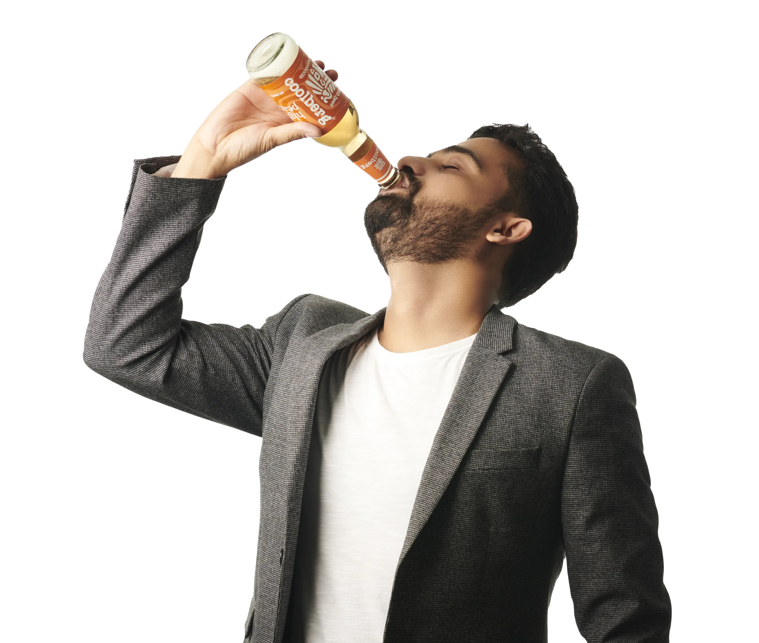 Man in gray blazer and white shirt drinking from a bottle of Golden Eagle beer.