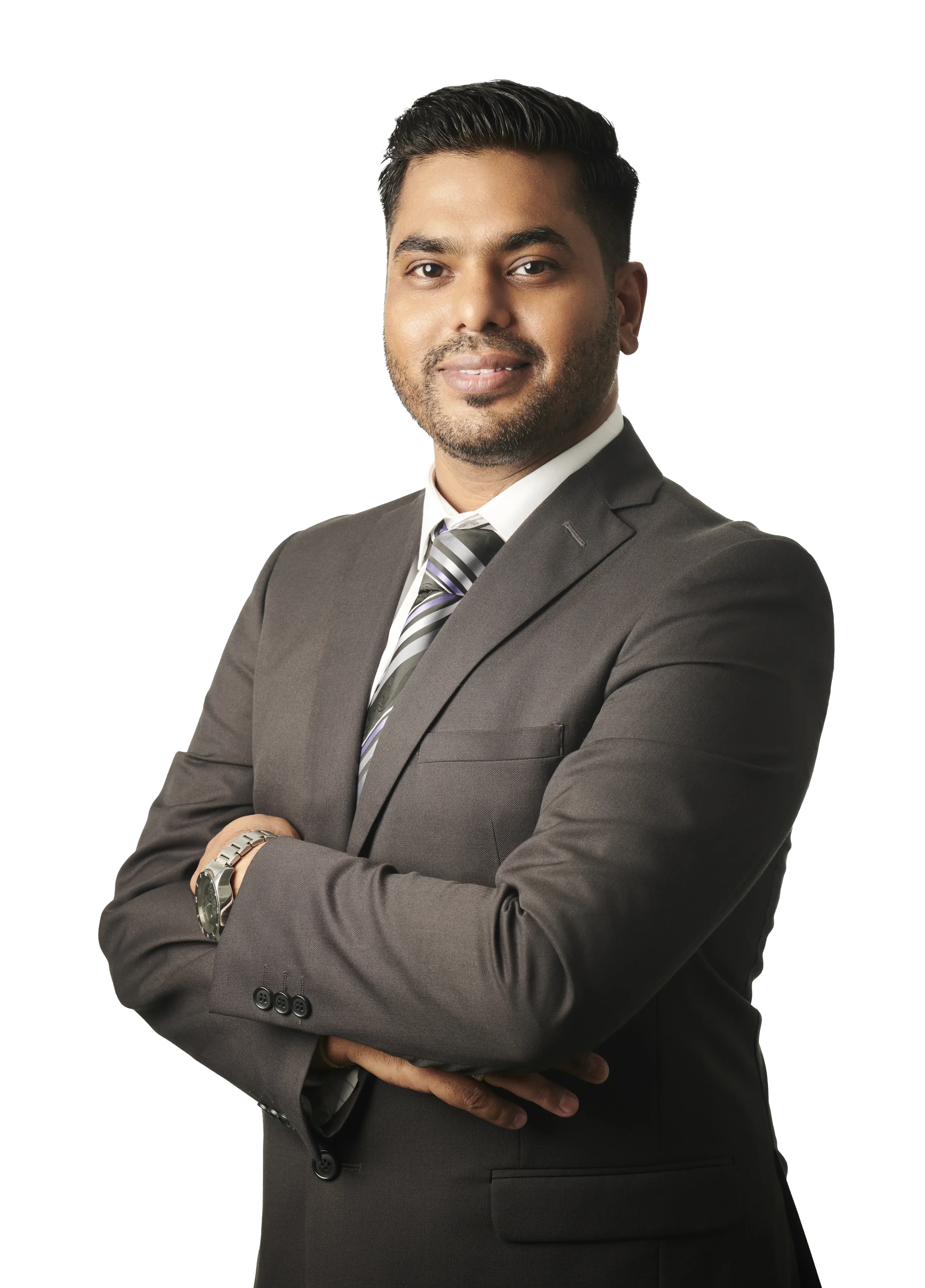 A man in a gray suit with a striped tie, standing with arms crossed against a white background.