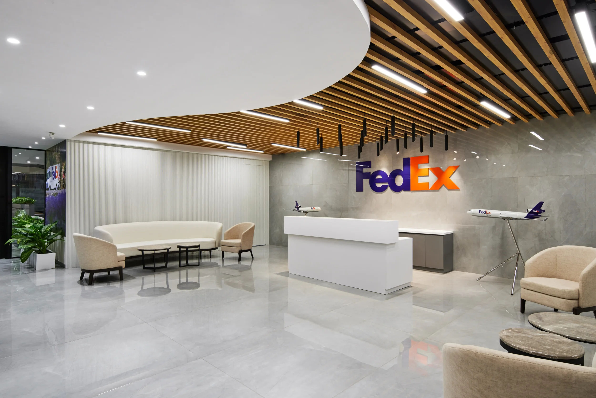FedEx office lobby with modern decor, seating area, reception desk, and model airplanes displayed near the wall.