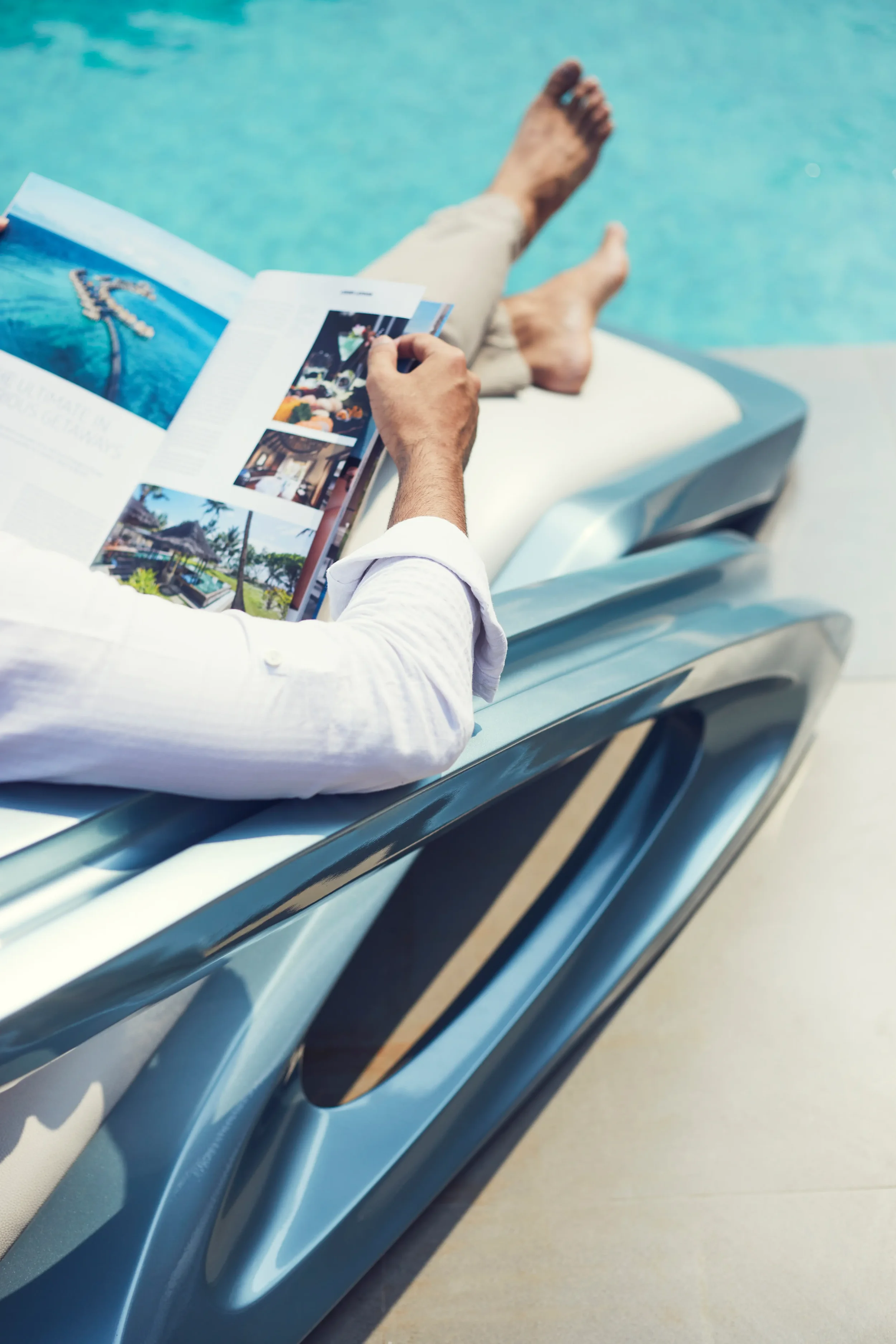 Person relaxing by a swimming pool, reading a travel brochure.
