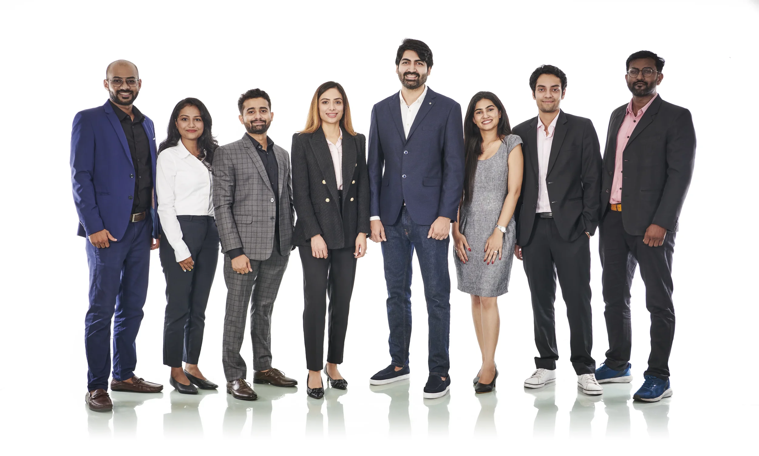 Group of eight professionally dressed people standing together against a white background.