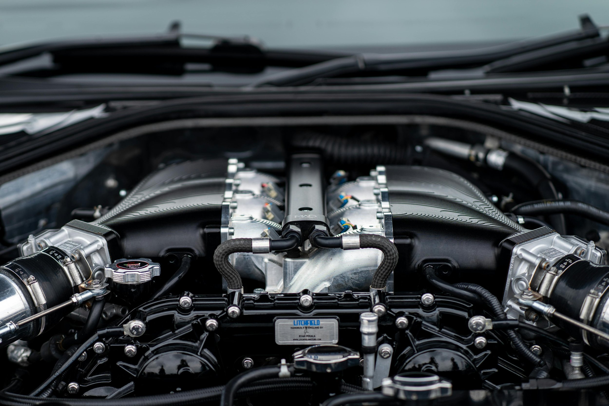 Close-up view of a high-performance car engine with metallic components, hoses, and wiring, under the hood.
