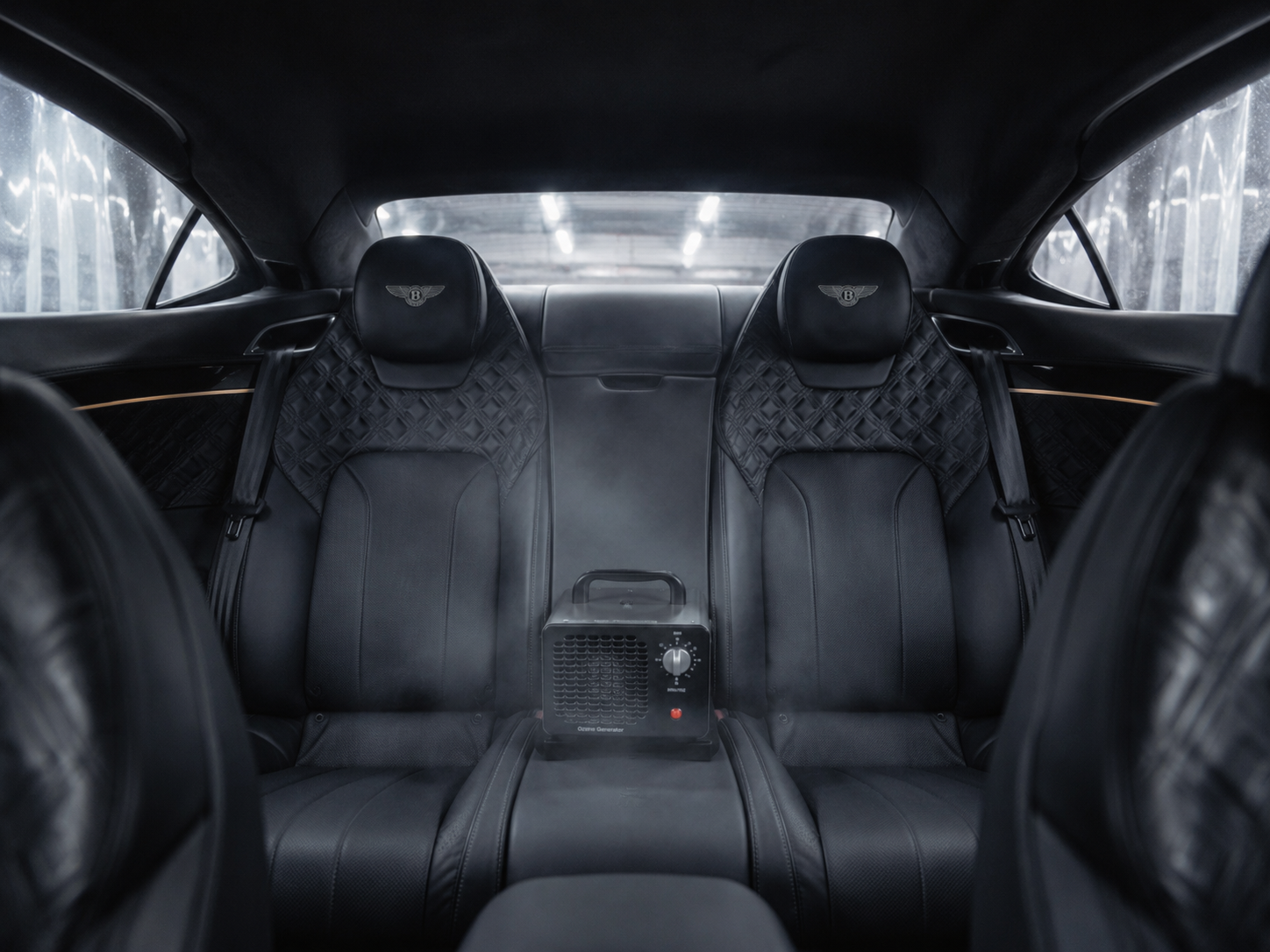 Interior of a luxury car showing black leather seats with quilted headrests, a small heater in the center, and rear window view.