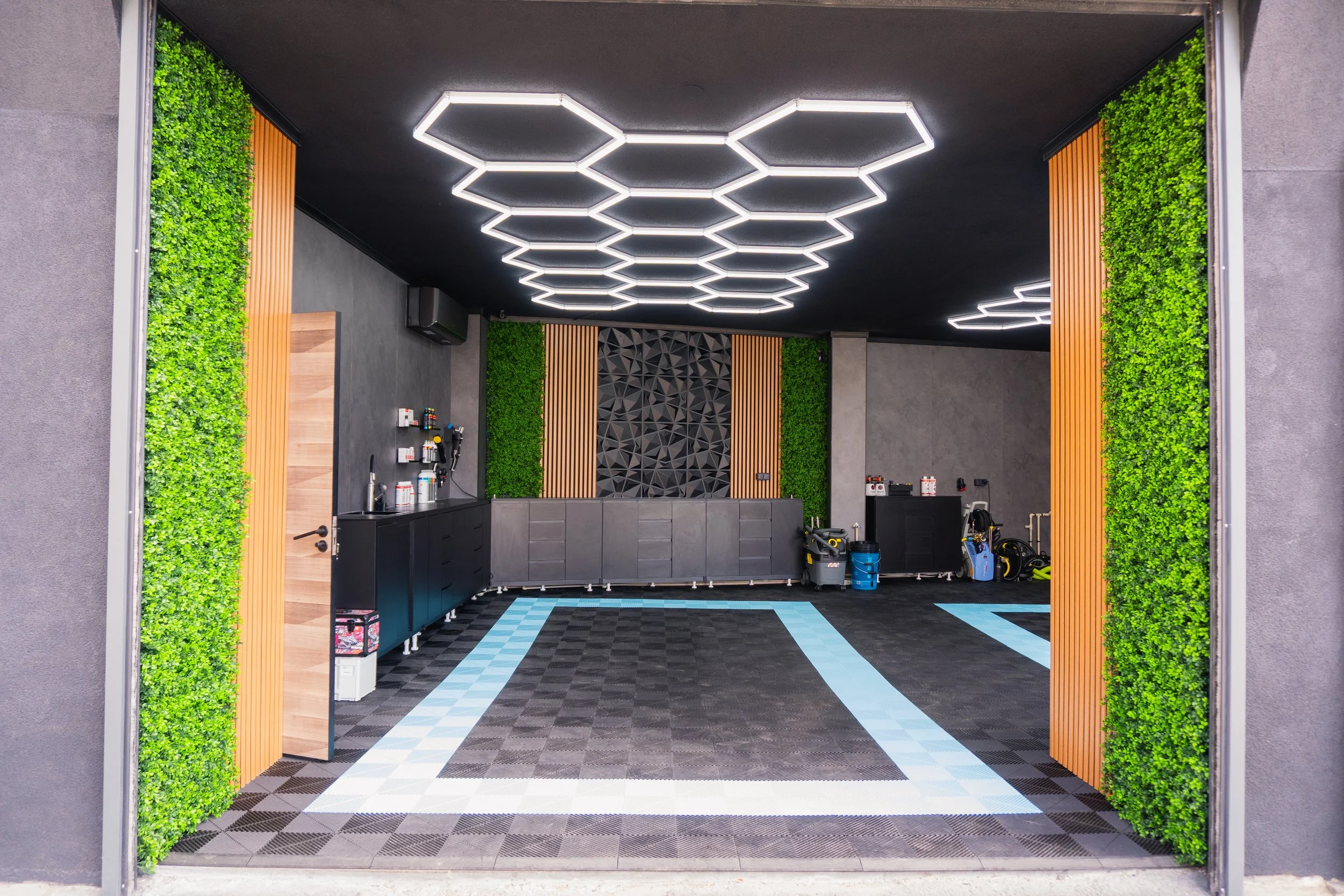 Modern garage interior with black ceiling, green wall accents, and a checkered floor.