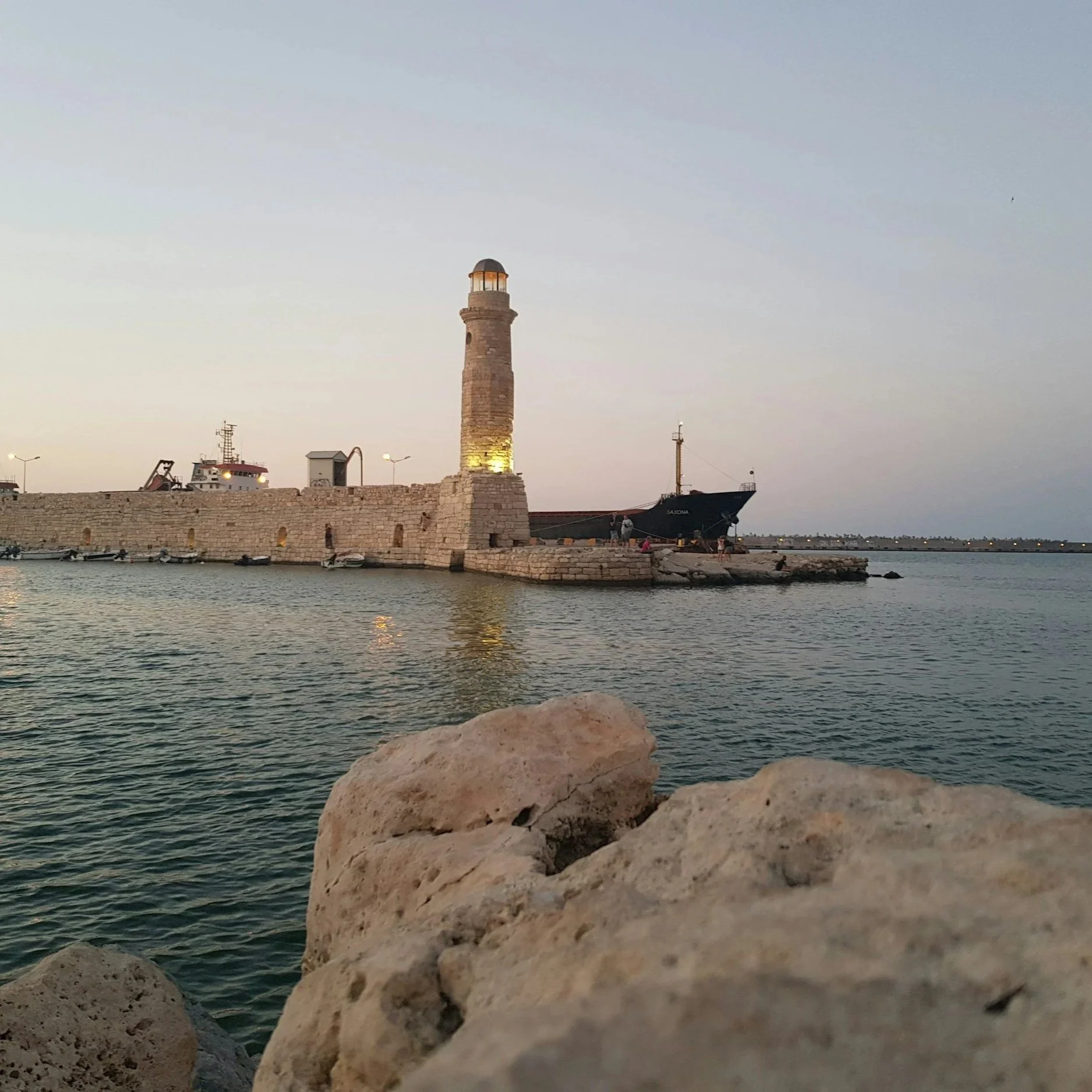 Lighthouse in Rethymno old harbour with rock in front.