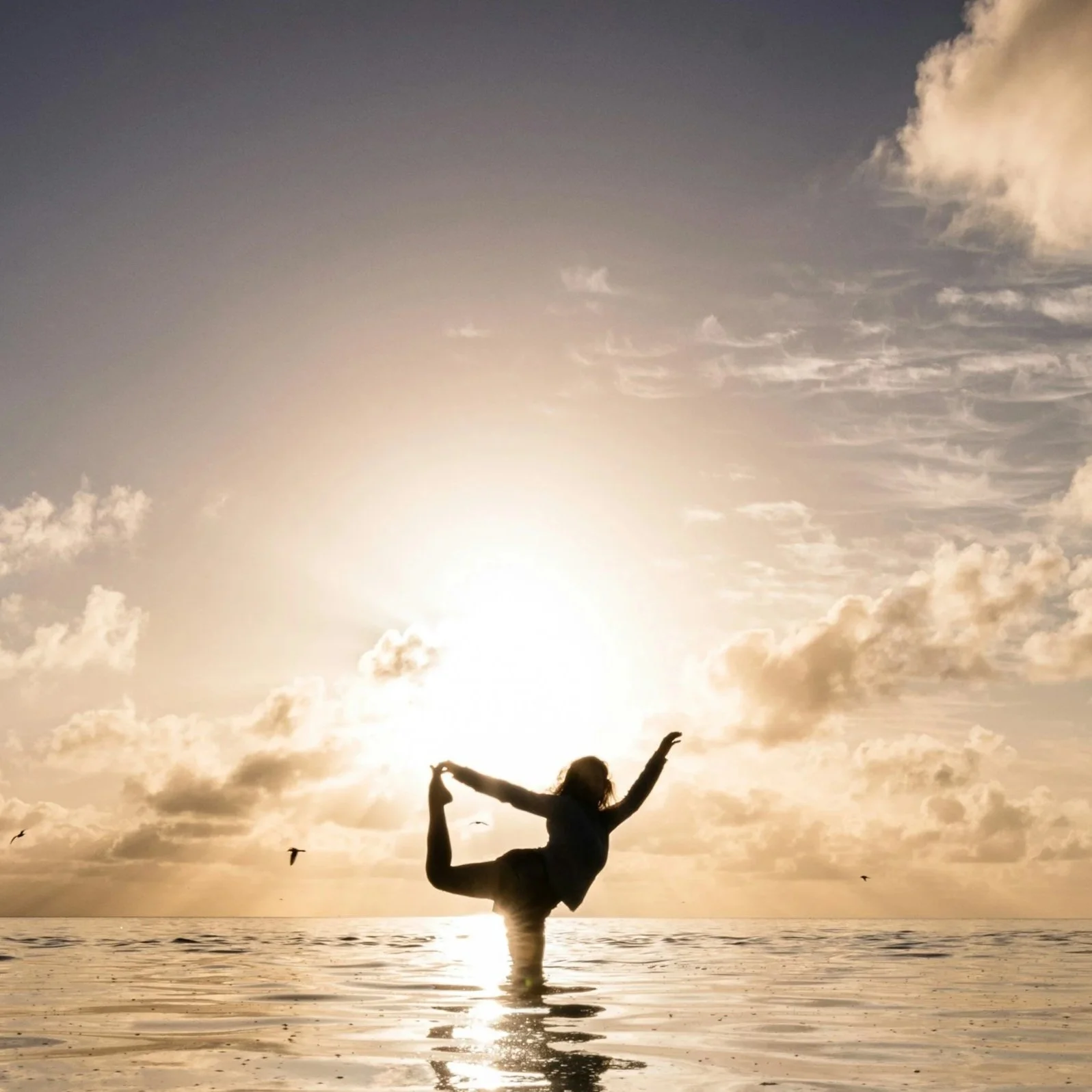 Woman practicing yoga standing on one leg and touching foot with hand in the Libyan Sea, Crete.