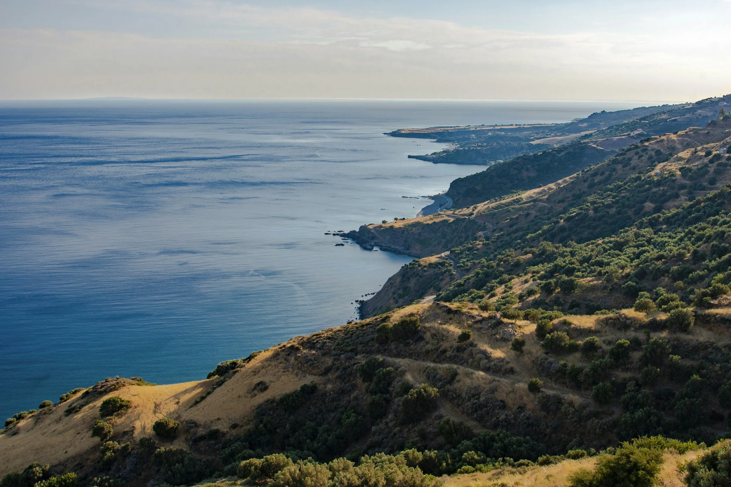 Aerial image of the coastline in Crete with mountains touching the sea.