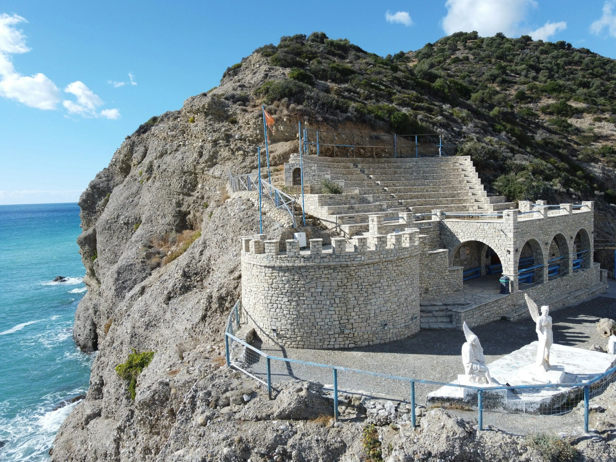 Drone shot of the amphitheatre of Agia Galini with cliffs in the back and the sea below.