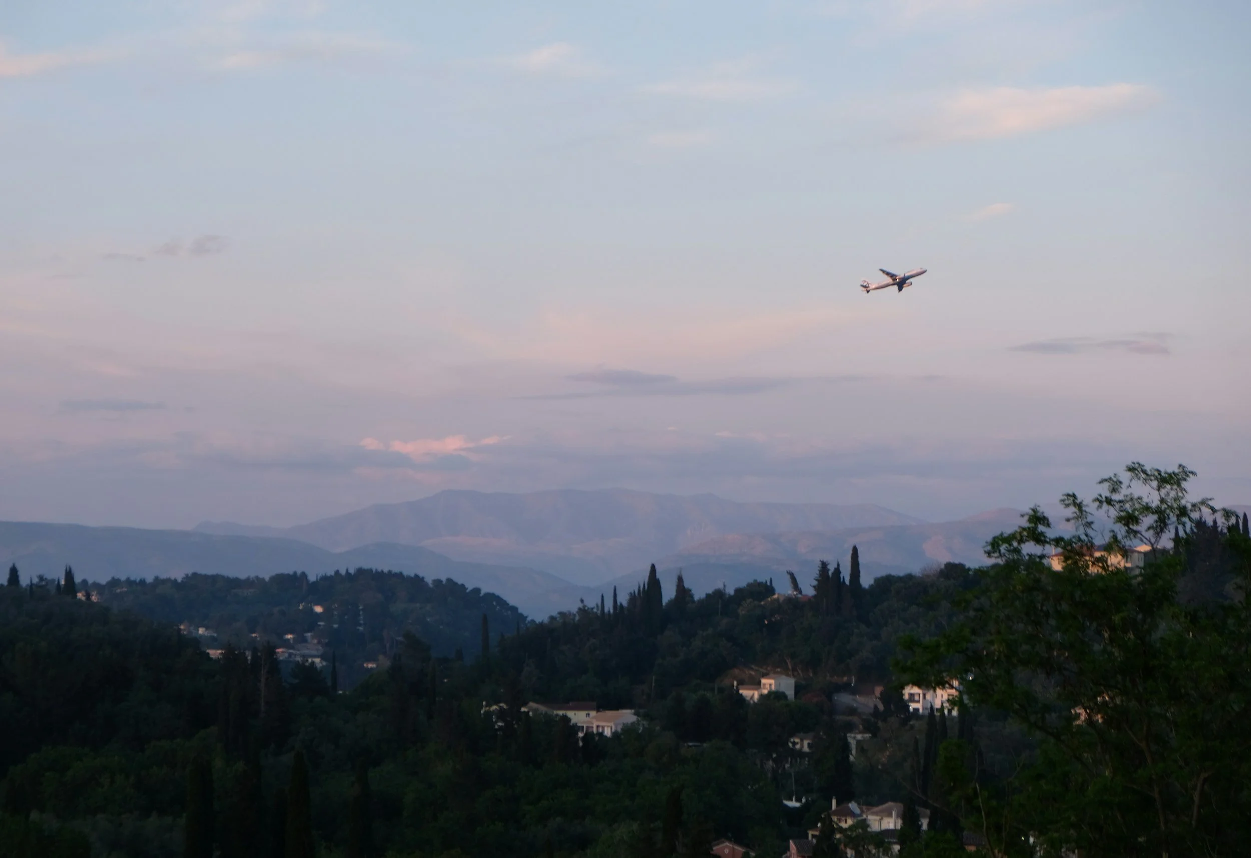 An airplane is flying over Crete during sunset after departing from Heraklion Airport.