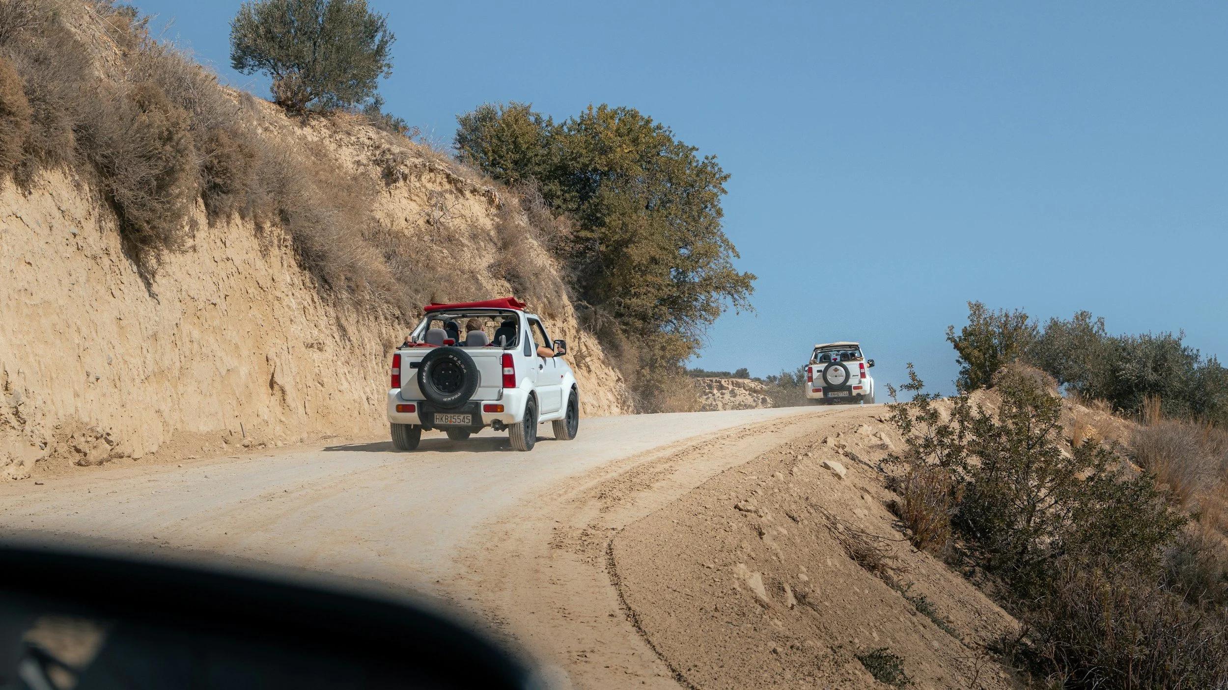Two offroad cars driving along a rural road in South Crete.