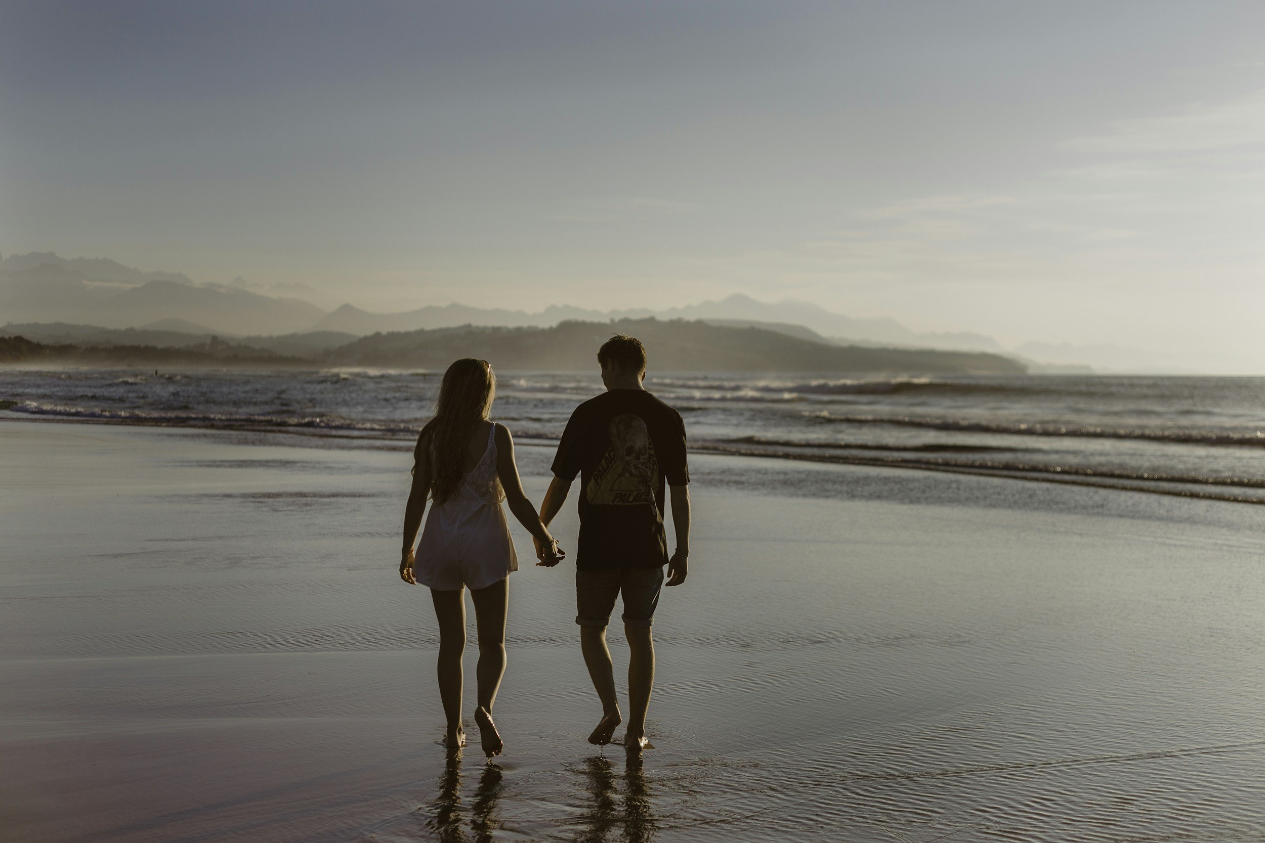 Couple walking down a sandy beach in Crete hand in hand