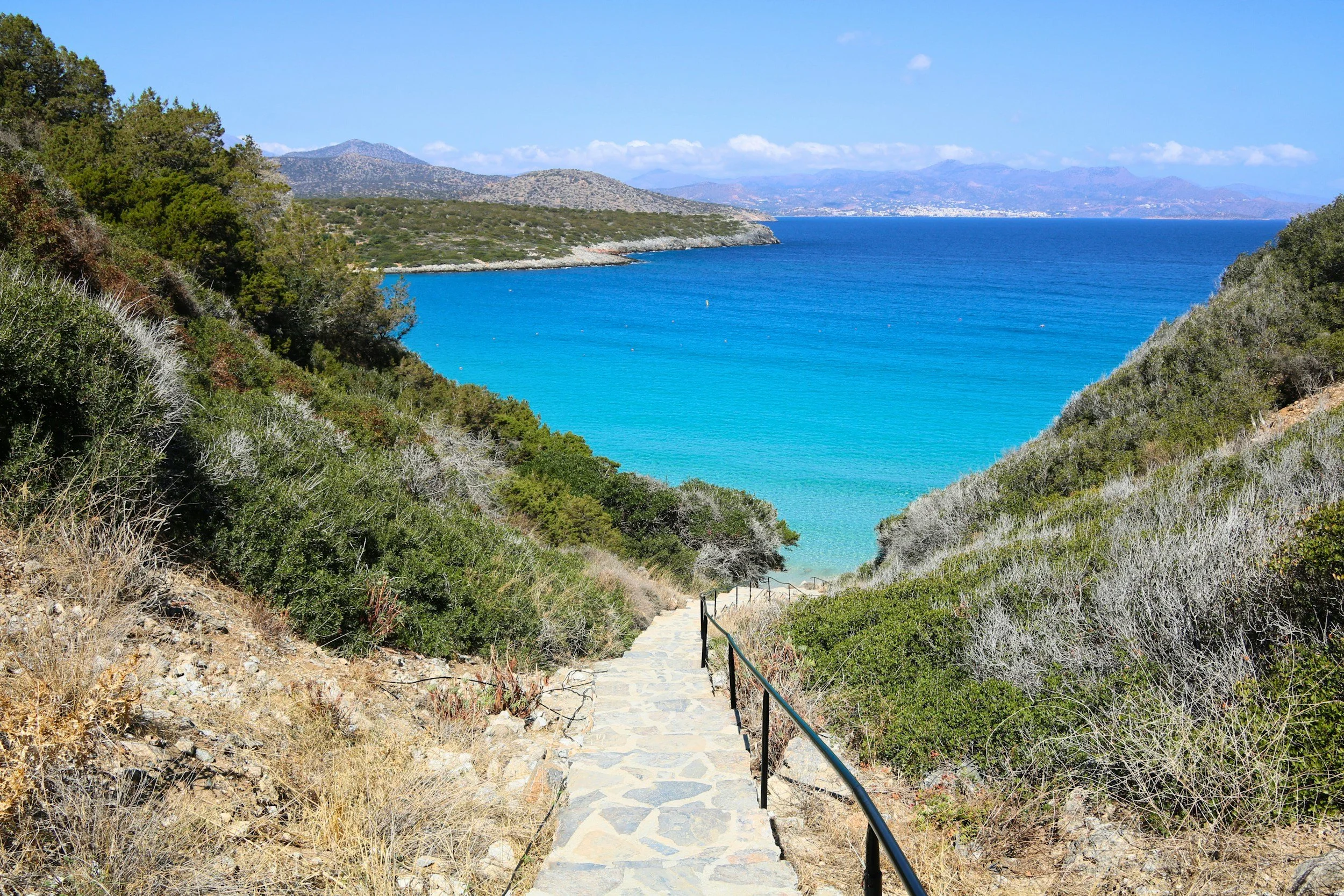 Path in South Crete past green hills towards the Libyan Sea and distant mountains.