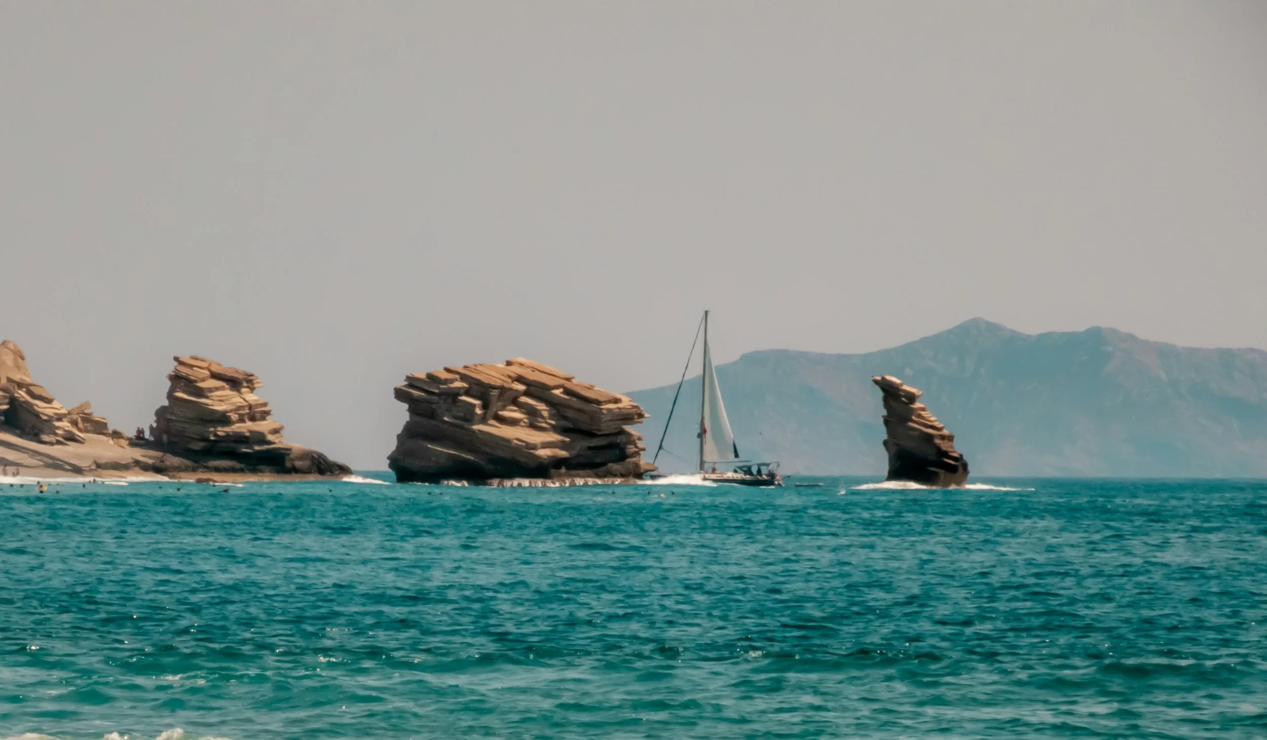 The three offshore rock formations of Triopetra emerge from turquoise water on Crete's south coast.