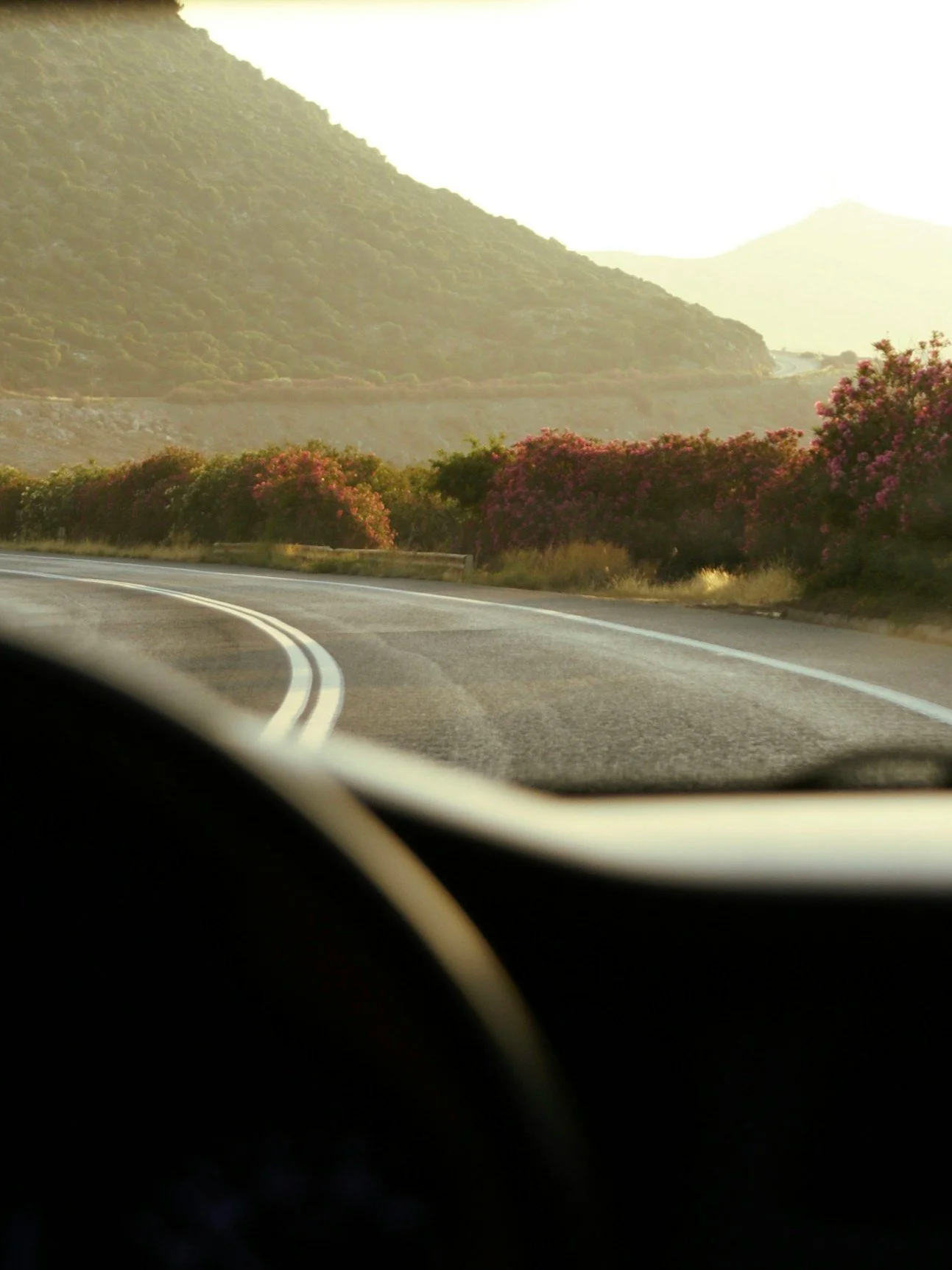 Car driving on an asphalt road on the coast of South Crete at sunset.