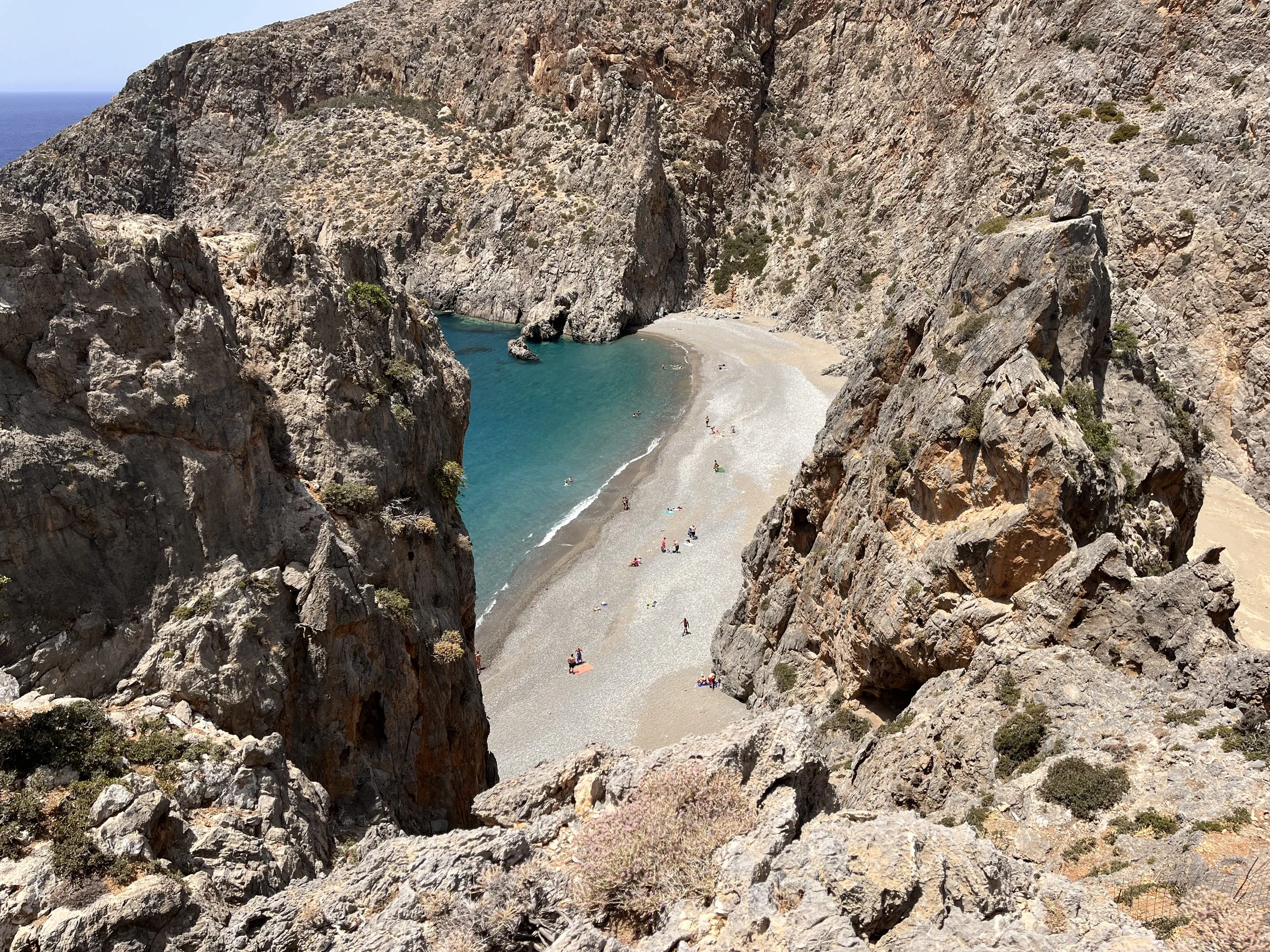 Sandy beach at Agiofaraggo Gorge seen through rock formations.